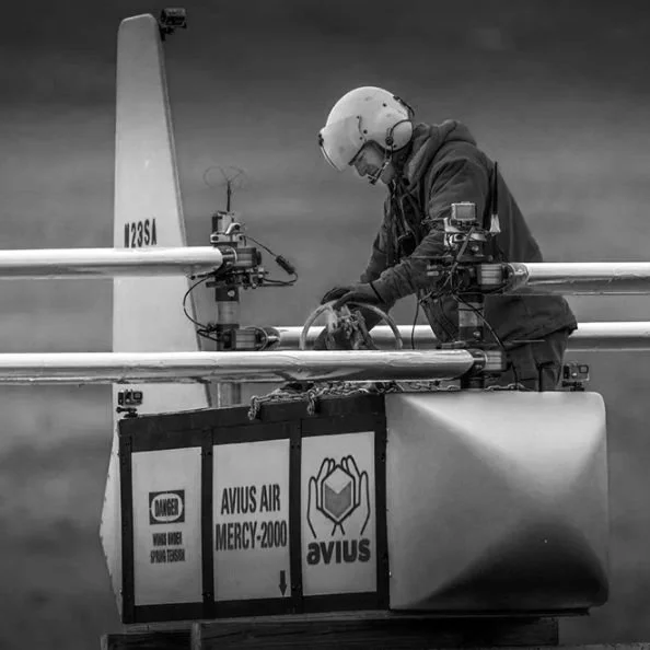 Person in helmet working on drone labeled "Avius Air Mercy-2000."