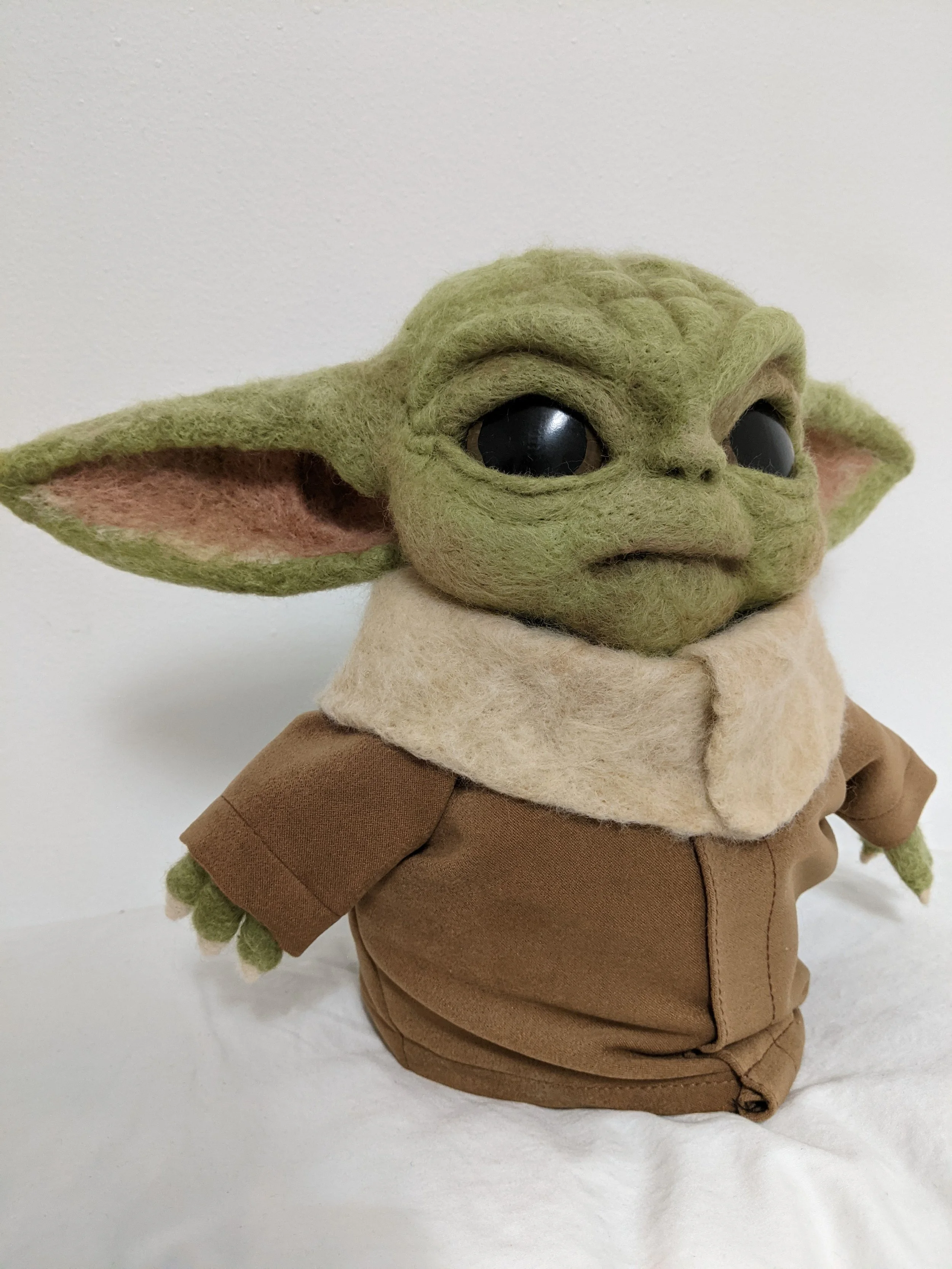 Ce bébé Yoda est taille réelle. Je lui ai incorporé un dispositif qui le fait parler lorsqu'on appuie sur sa main, permettant d'enregistrer le message de notre choix.