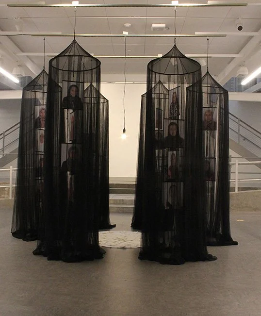 Collapse, 2022, fabric, safety pins, archival ink on mylar, muslin bags, embroidery thread, hanging single light fixture, light bulb, 96" x 28" x 28" (each of 6 structures) Muslin bag mandala 48” circumference