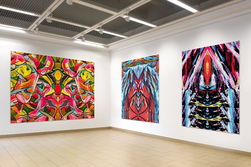 Three paintings, one of the left, two on the right, hanging on a lightly colored gallery wall. The artwork featured is "Amarie", "Tribe" and "Warframe."