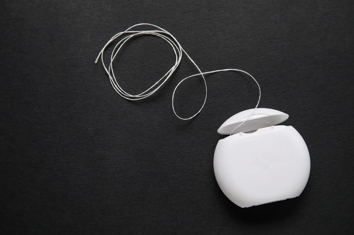 Container of floss with floss flowing out of it