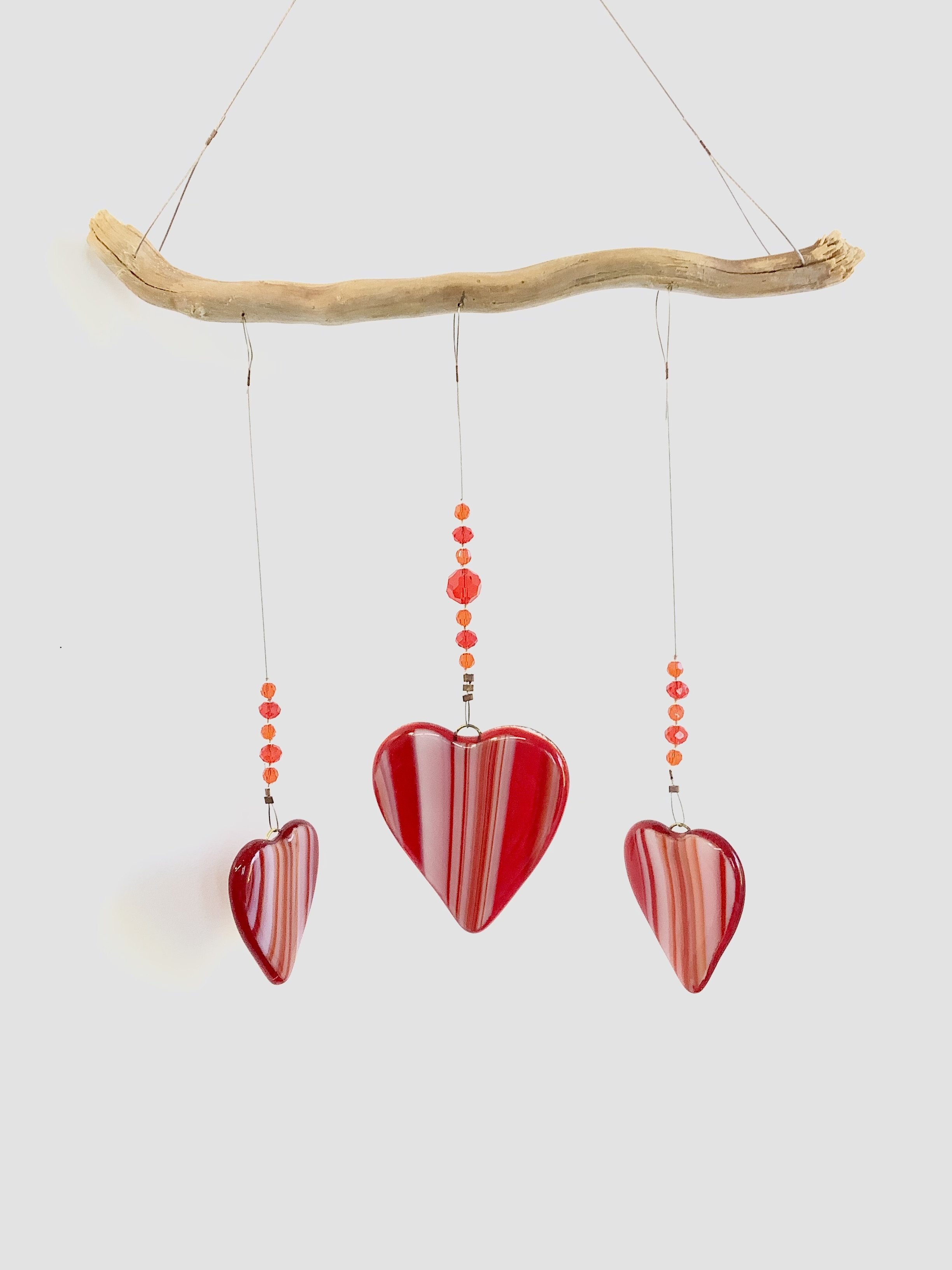 $65
Red and orange swirly fused glass heart mobile with red, white, and orange beads. Middle heart is larger than two side hearts. Hangs 15"x8"from stainless wire and Vancouver Island driftwood. Contact to purchase.