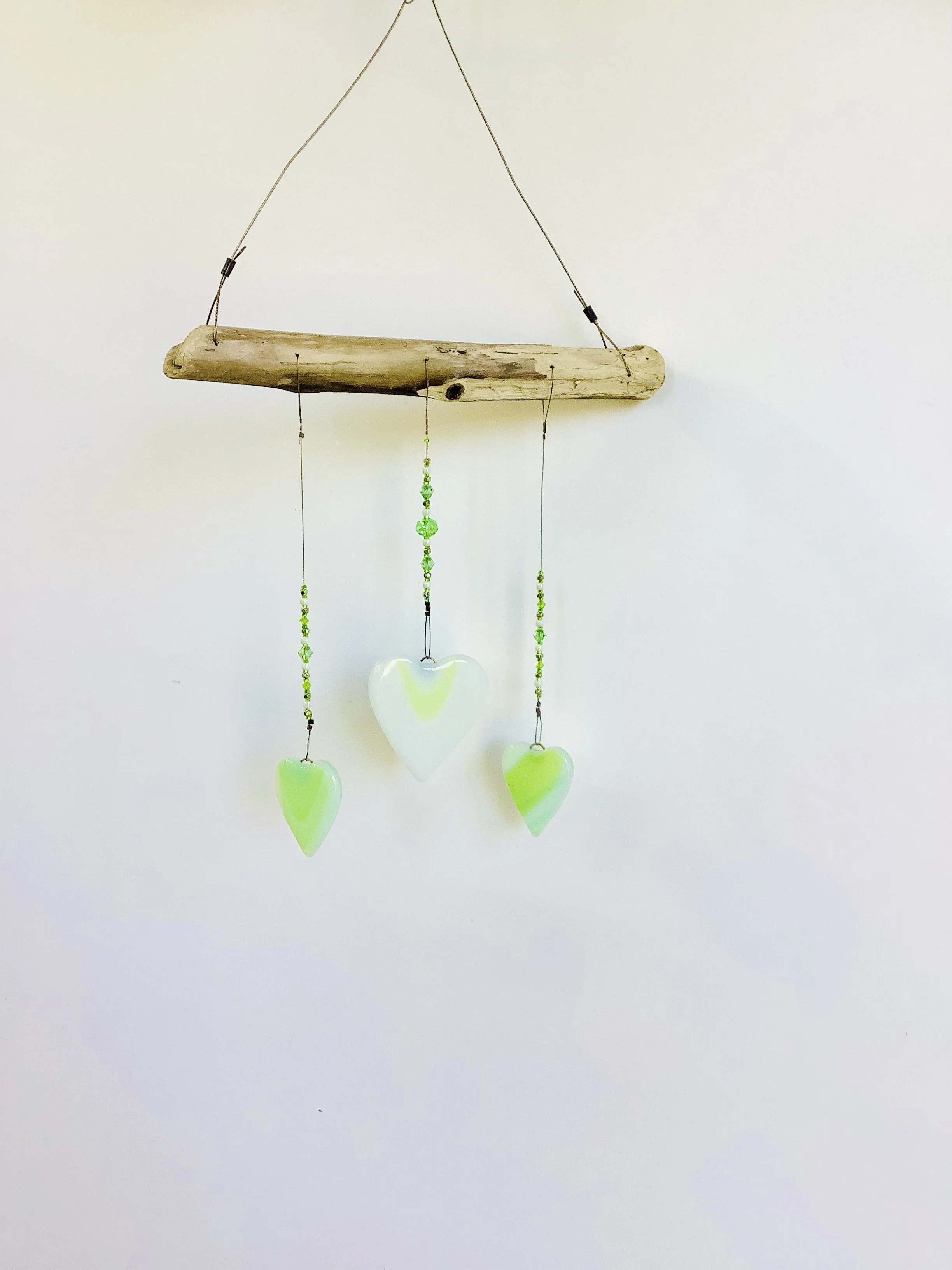 SOLD   $65
Green and white swirly fused glass heart mobile with green and white glass beads. Middle heart is larger than two side hearts. Hangs 17"x8" from stainless wire and Vancouver Island driftwood. Contact to purchase.