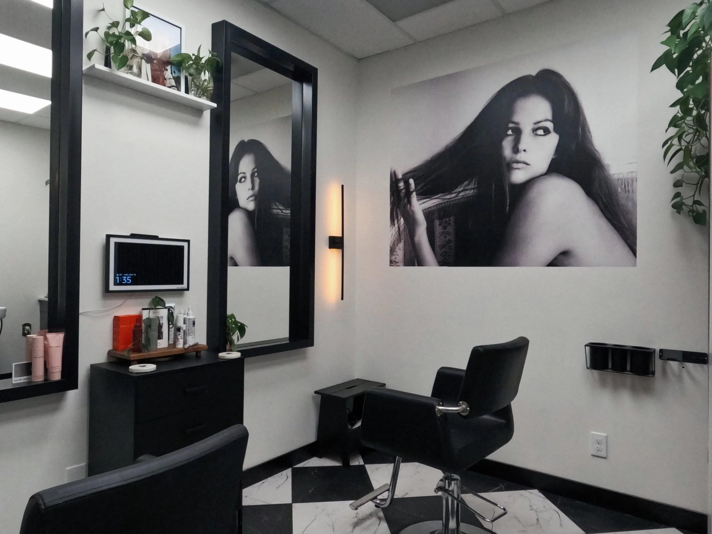 Modern hair salon interior at The Co-Artist Studio in Capitola, California, featuring a black-and-white editorial wall poster and styling station.