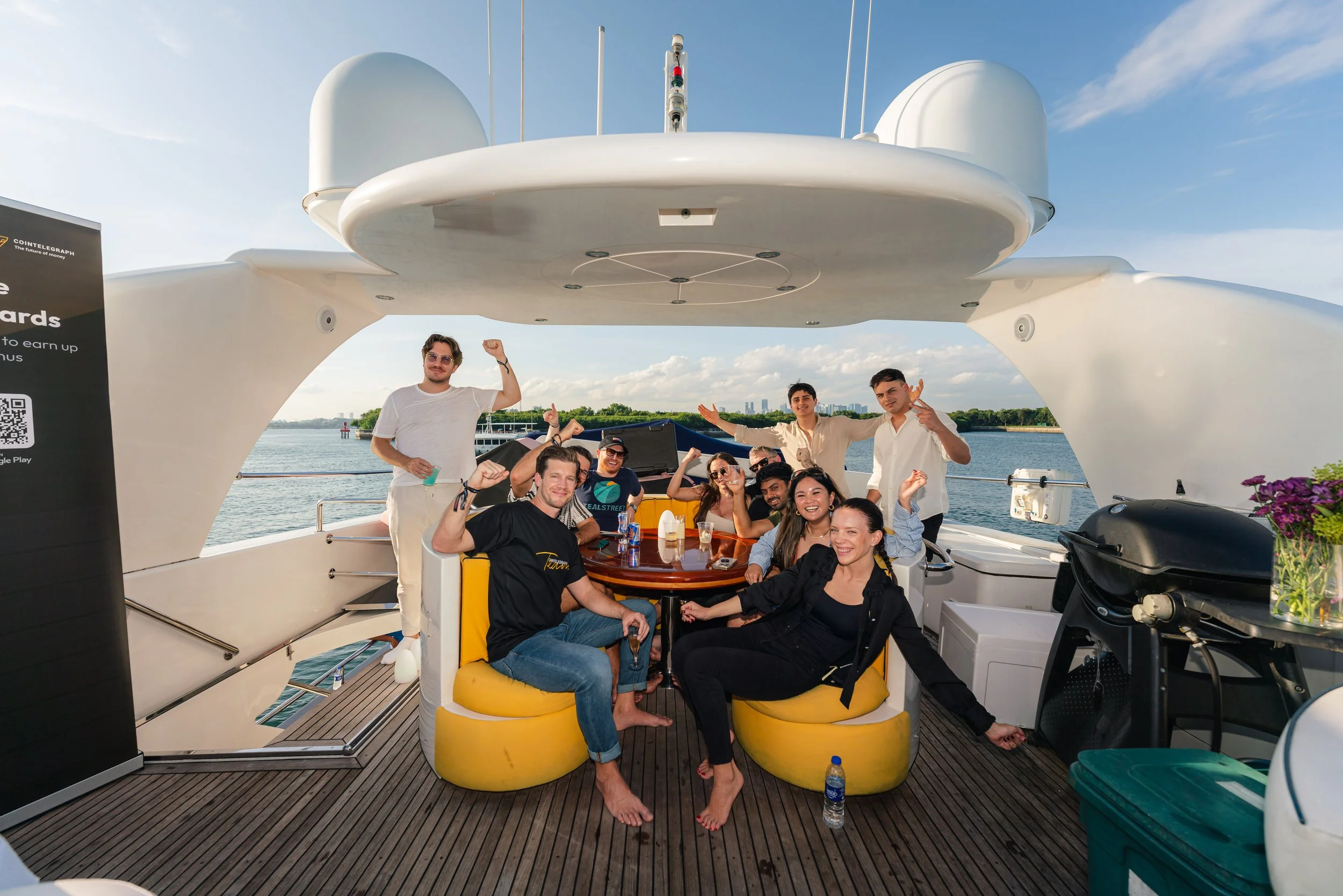 Group photo aboard a luxury yacht during a cryptocurrency networking event, with guests enjoying a relaxed waterfront gathering and marina views in a premium outdoor setting.