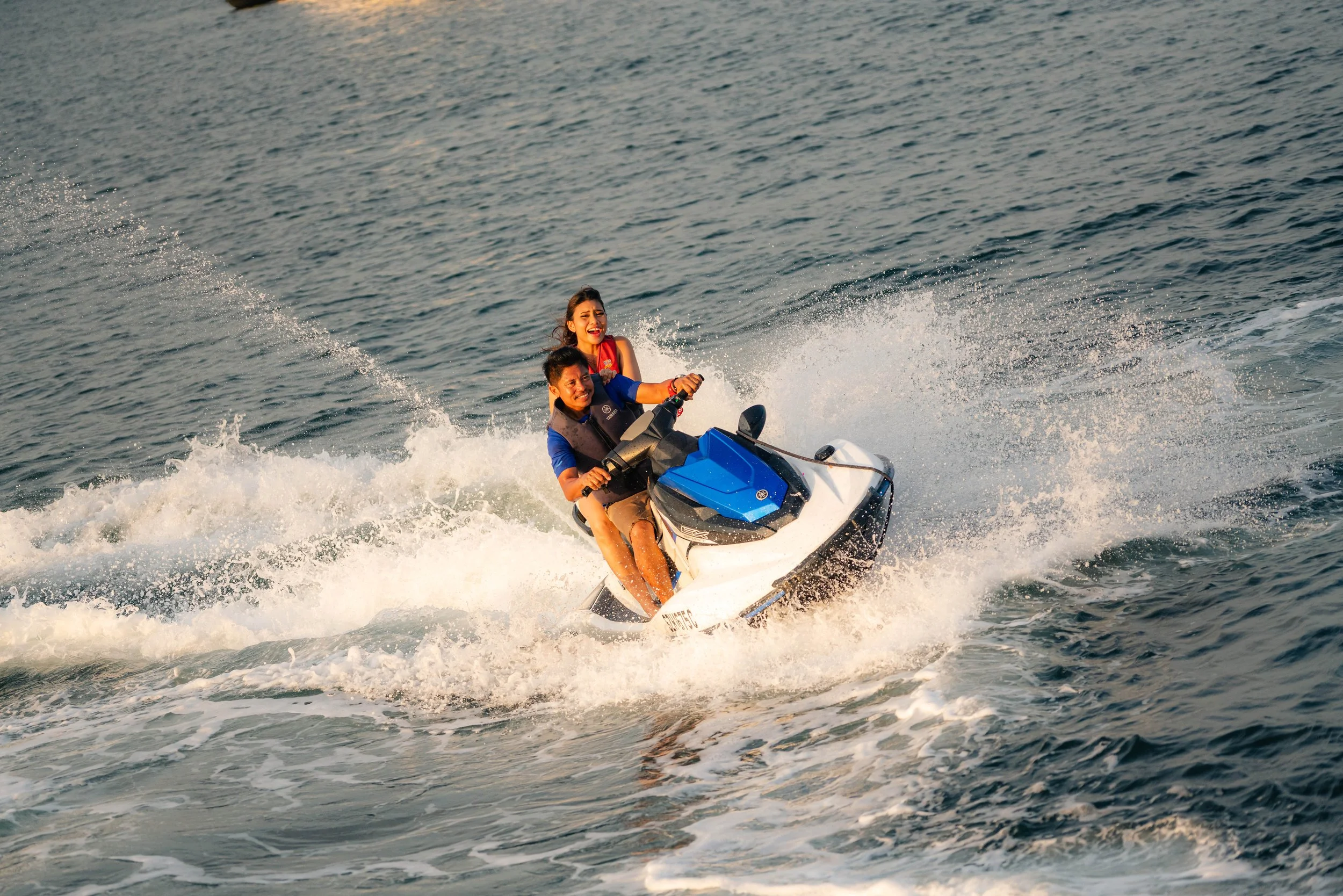 Guests enjoying a jet ski ride during a luxury yacht event in Singapore's Southern Islands, creating an exciting waterfront experience against the scenic coastline.