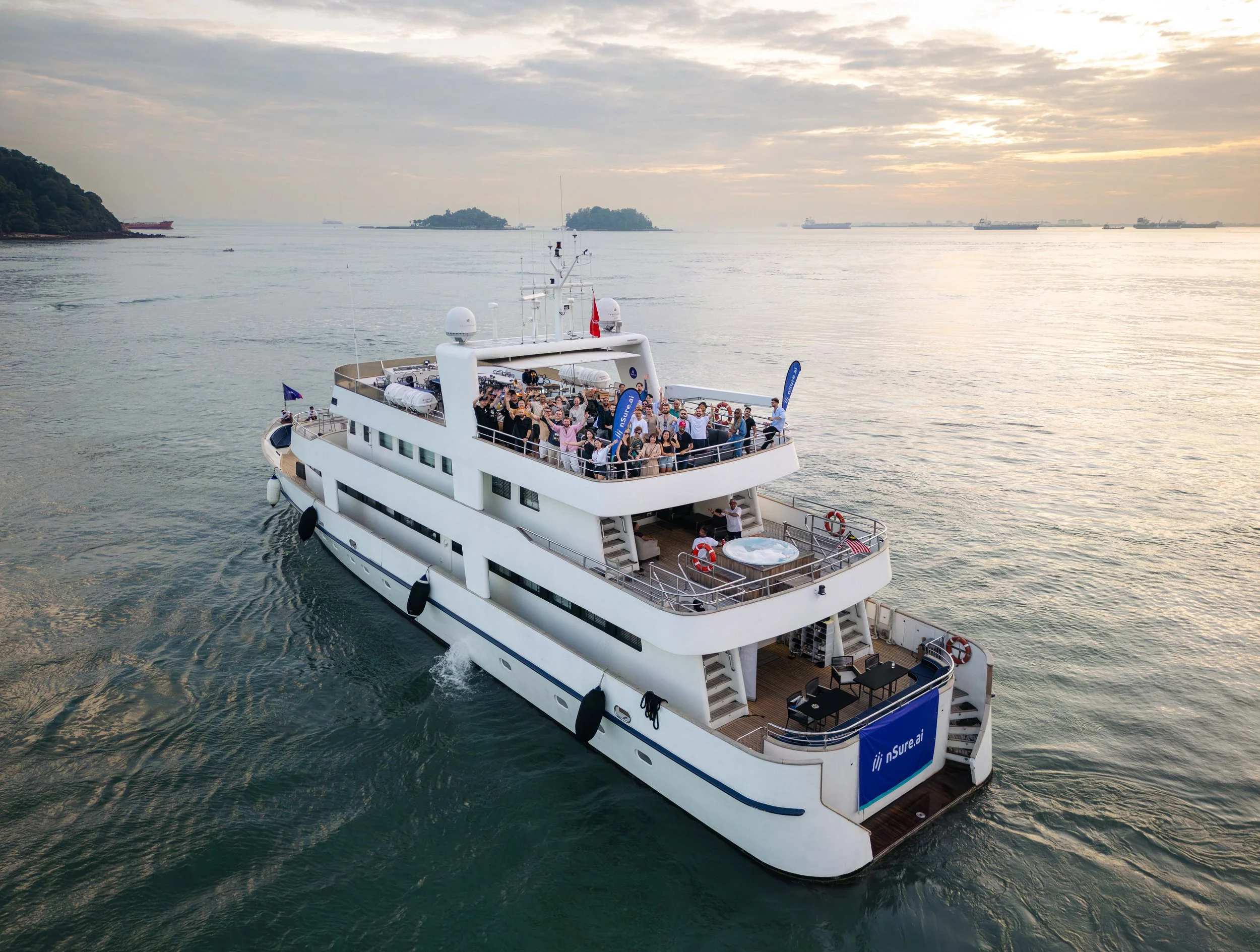 Aerial view of a luxury yacht hosting guests in Singapore's Southern Islands, showcasing a premium setting for private yacht events, corporate gatherings and waterfront celebrations at sunset.