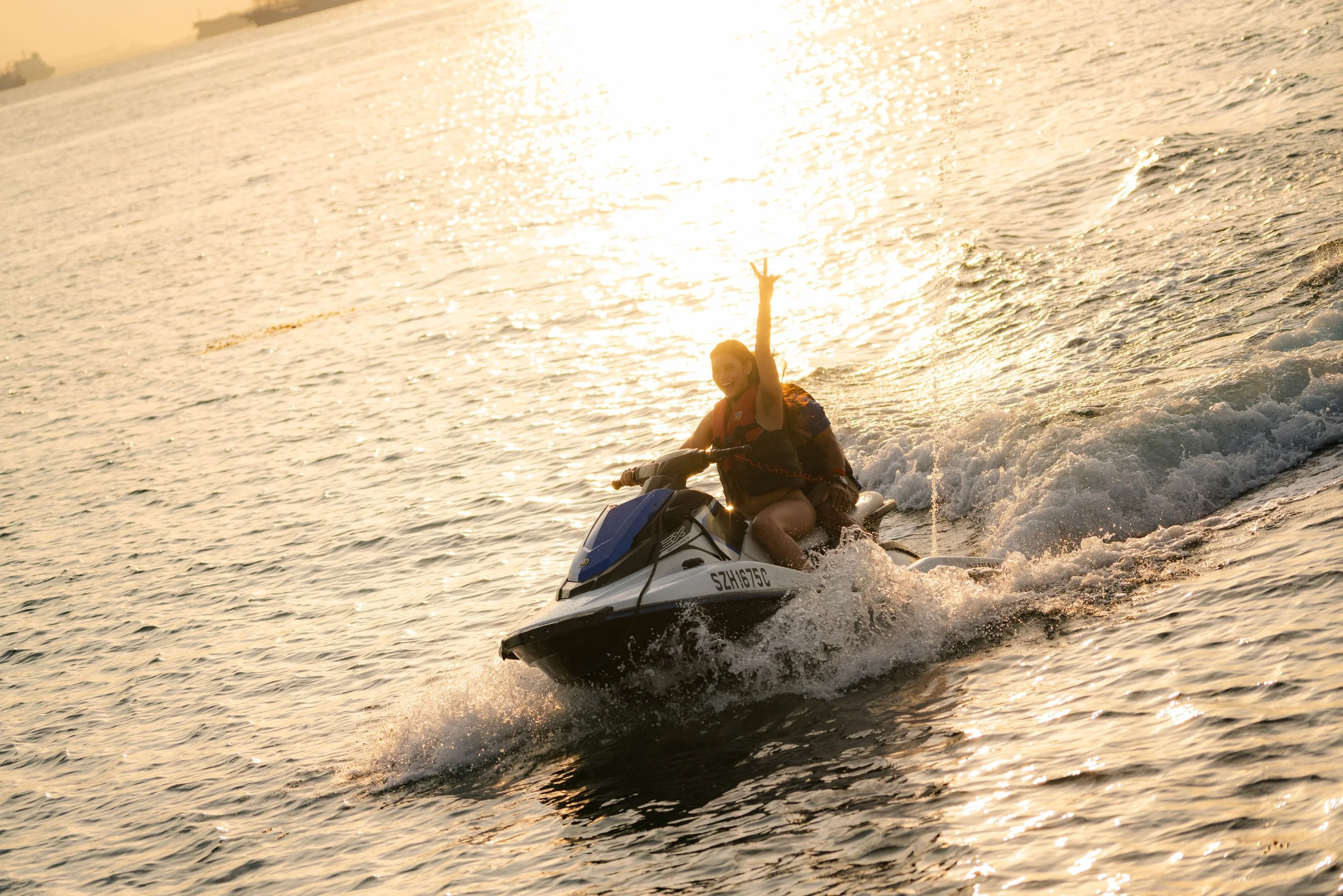 Guest riding a jet ski at sunset during a luxury yacht event in Singapore's Southern Islands, enjoying an exciting waterfront adventure against the golden evening light.