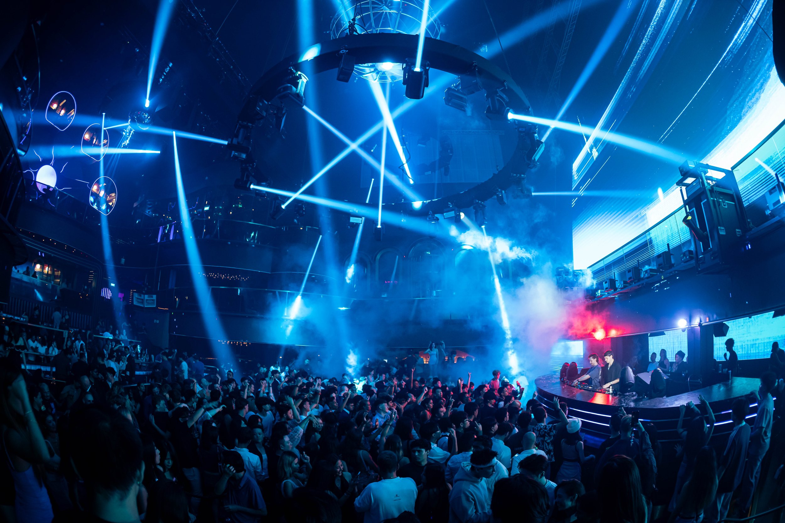 DJ Lucas & Steve performing live at Marquee Singapore as blue laser beams illuminate a packed dance floor, creating an immersive electronic music experience with dynamic stage lighting and energetic nightlife atmosphere.