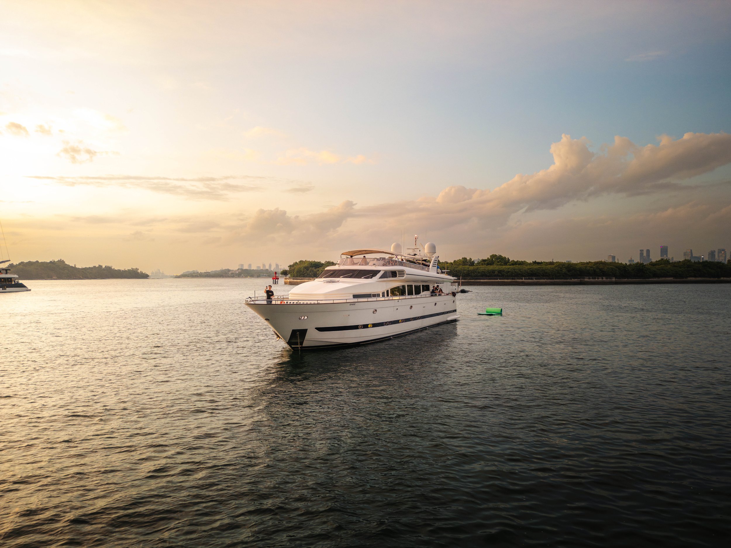Luxury motor yacht cruising through Singapore's Southern Islands during golden hour, showcasing a premium waterfront setting for private yacht charters, corporate events and luxury lifestyle experiences.