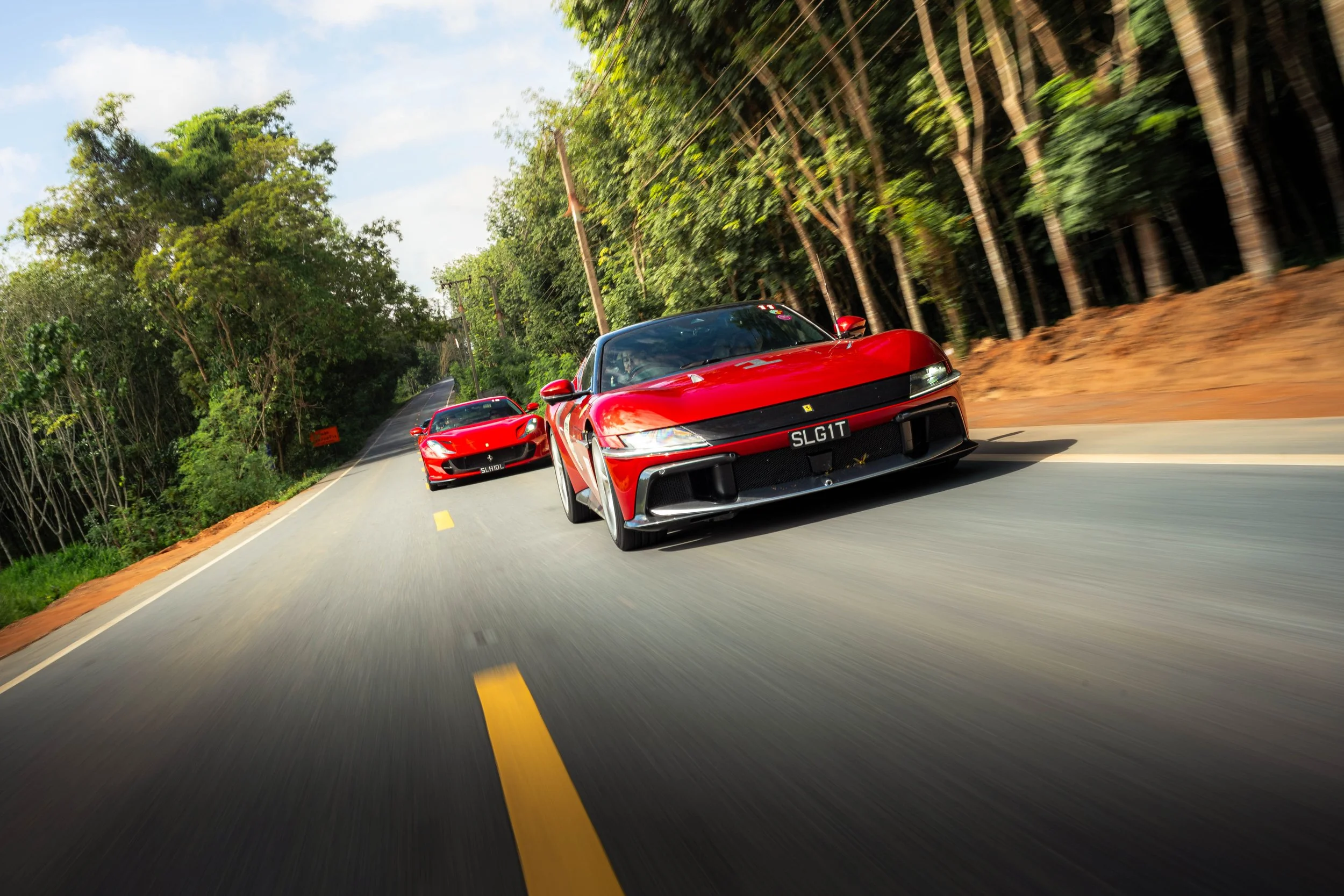 Red Ferrari 12Cilindri leading the Ferrari Owners' Club Singapore convoy through a tree-lined road in Krabi, Thailand during the Ferrari Owners' Club Singapore Overseas Drive.