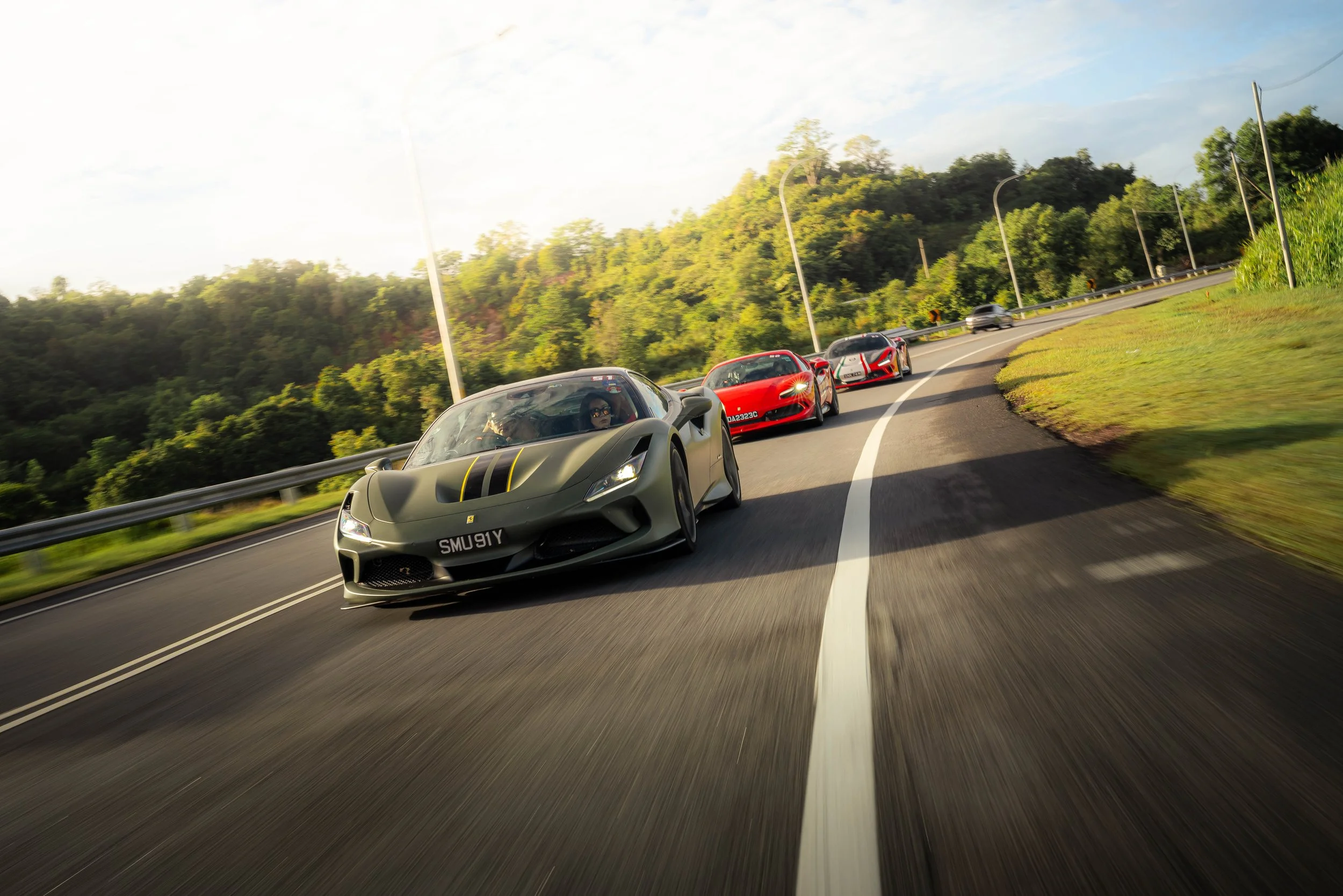 Matte green Ferrari leading a convoy of Ferraris through scenic mountain roads in Krabi, Thailand during the Ferrari Owners' Club Singapore Overseas Drive.