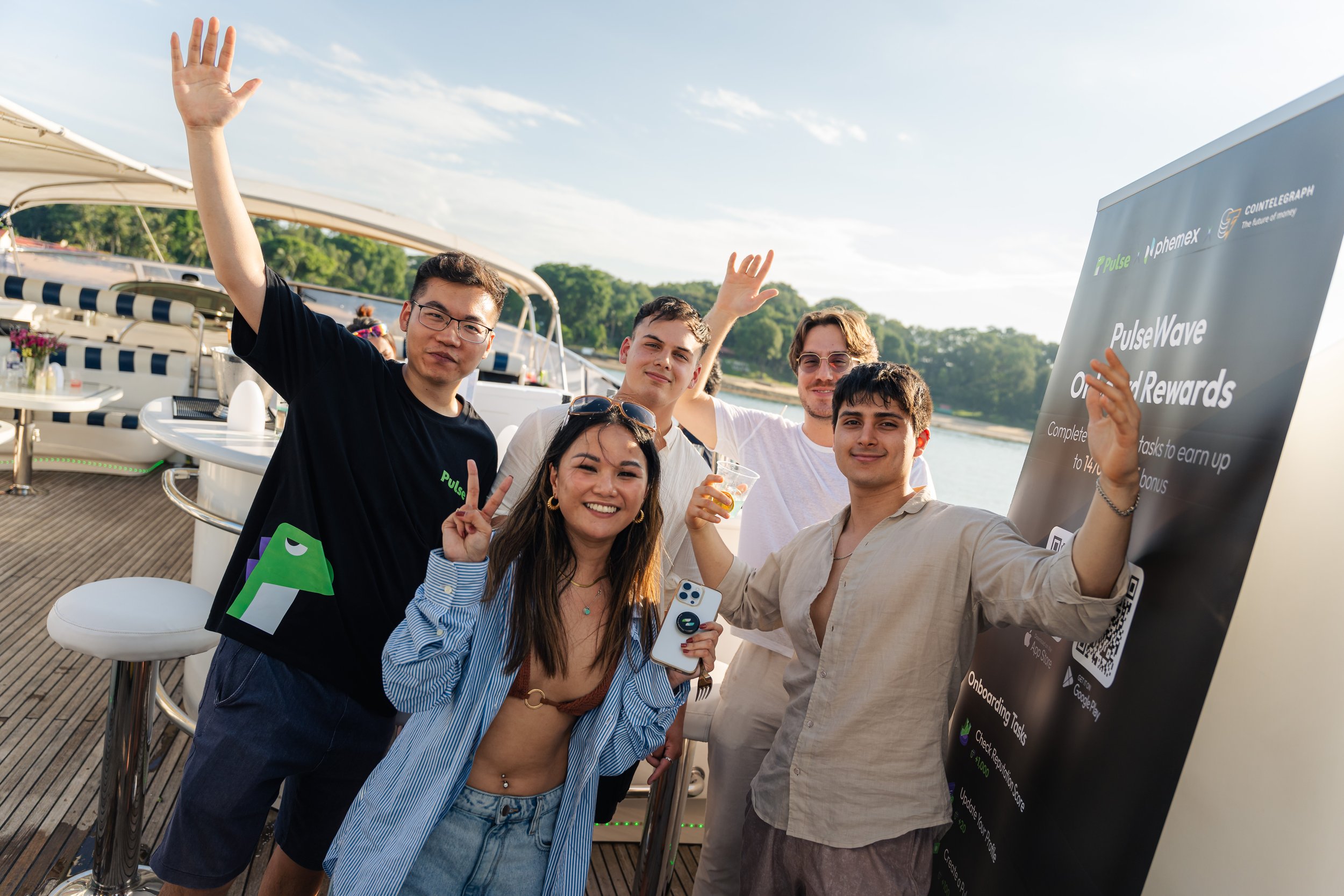 Guests posing together aboard a luxury yacht during a cryptocurrency networking event, enjoying a relaxed waterfront gathering under clear blue skies.