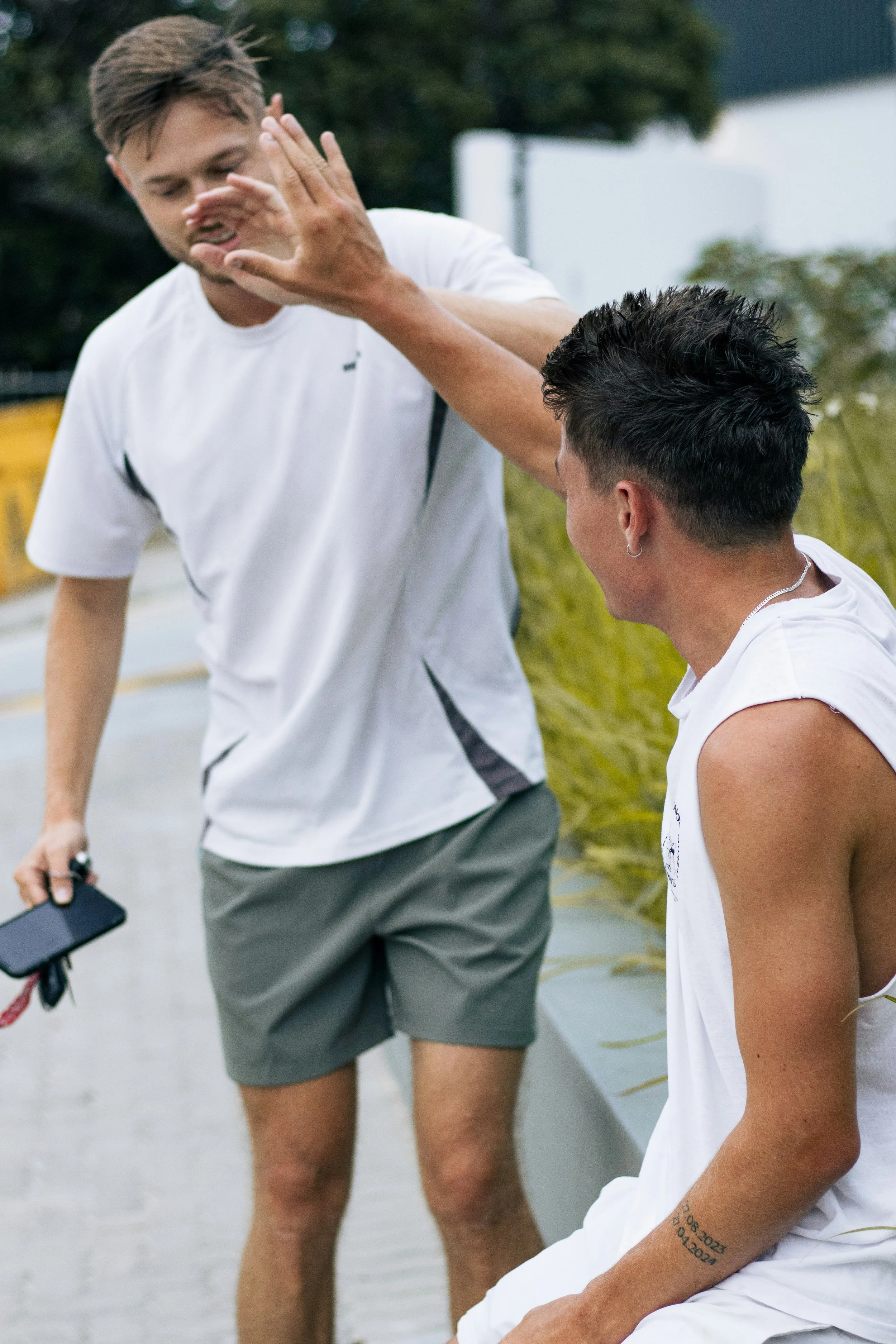 Two young men giving each other a high five outdoors.