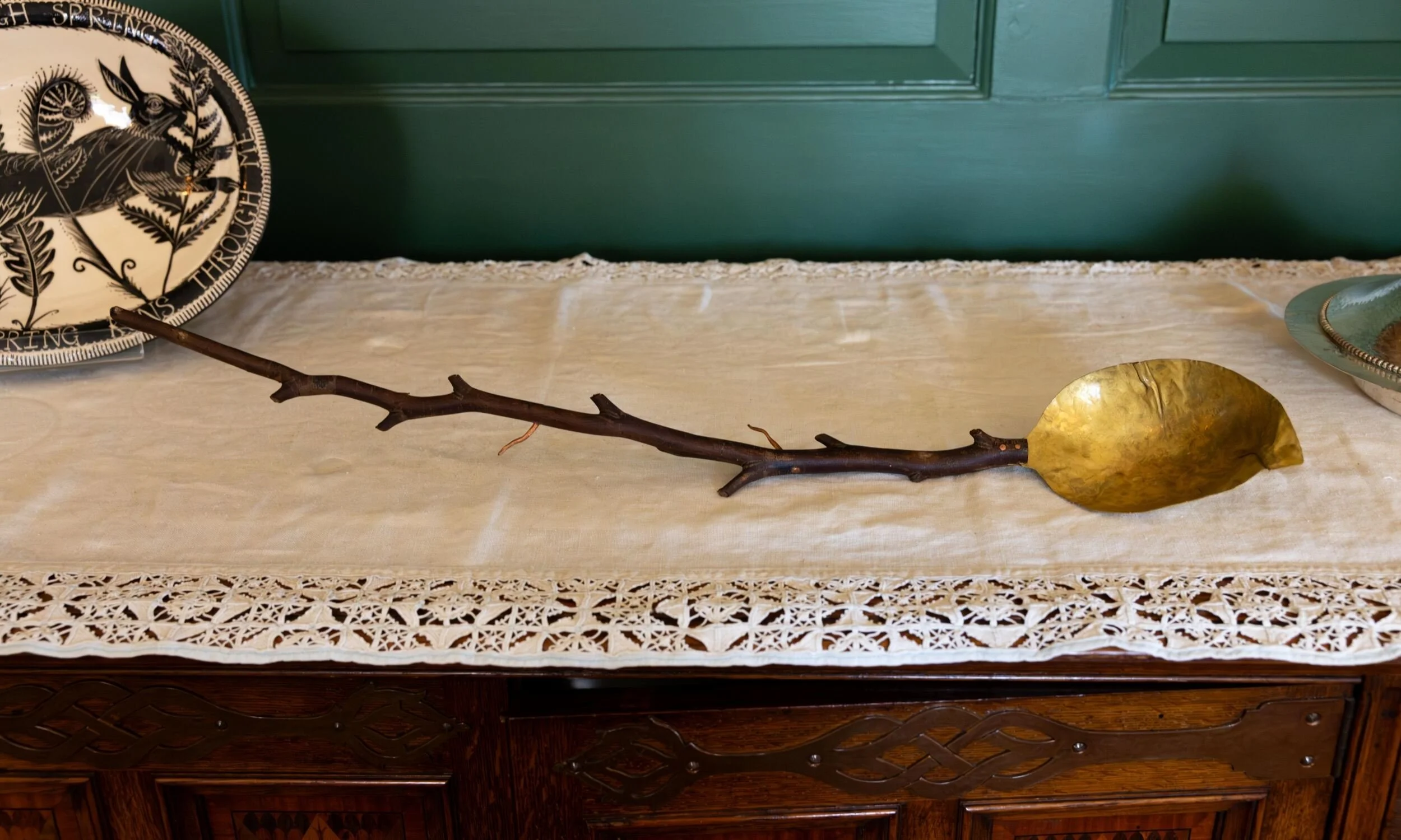Contemporary artwork combining a natural branch and brass form displayed at Inspired by Standen: The Future of Arts & Crafts