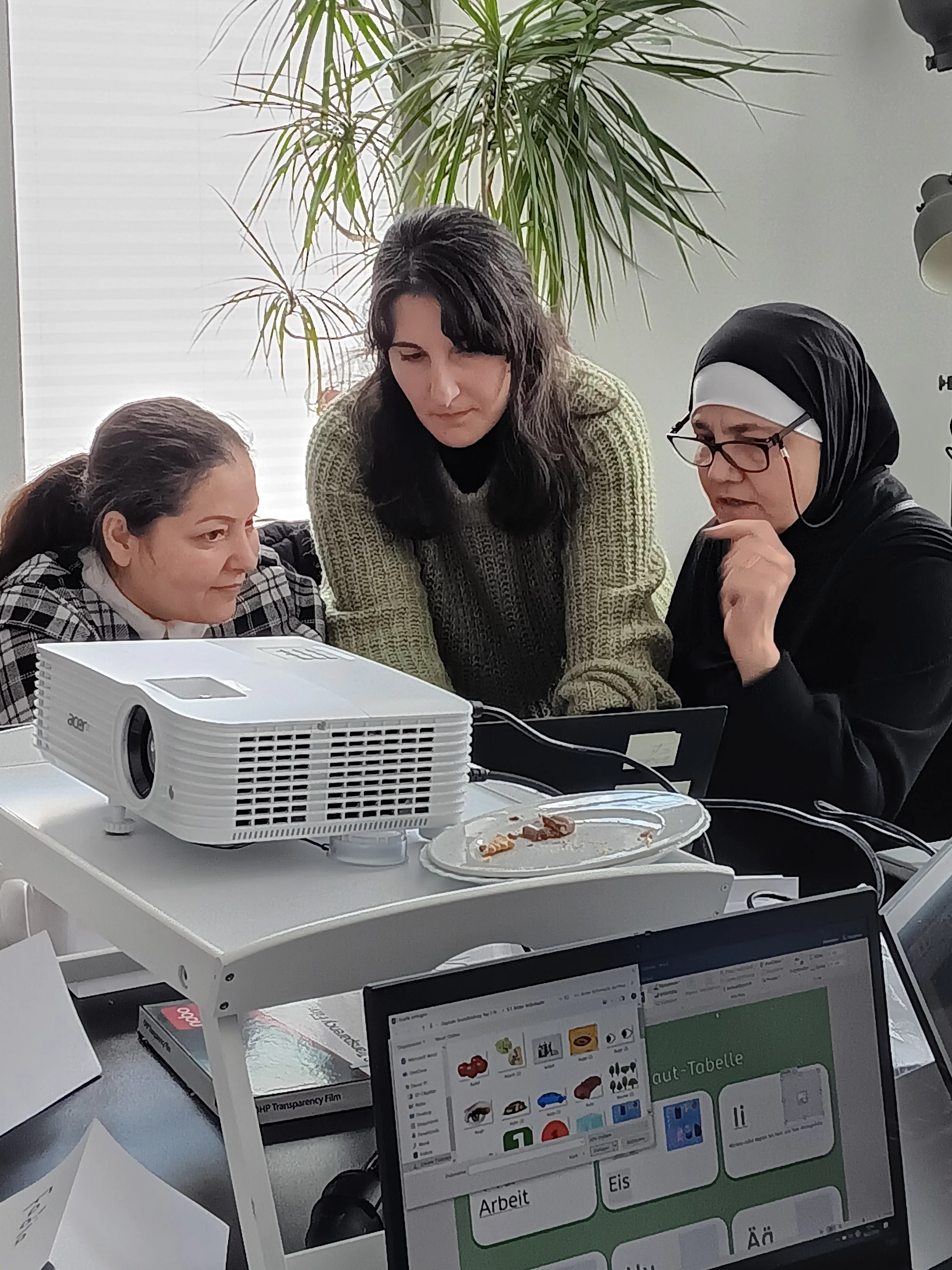 Drei Frauen schauen gemeinsam auf einen Laptop.