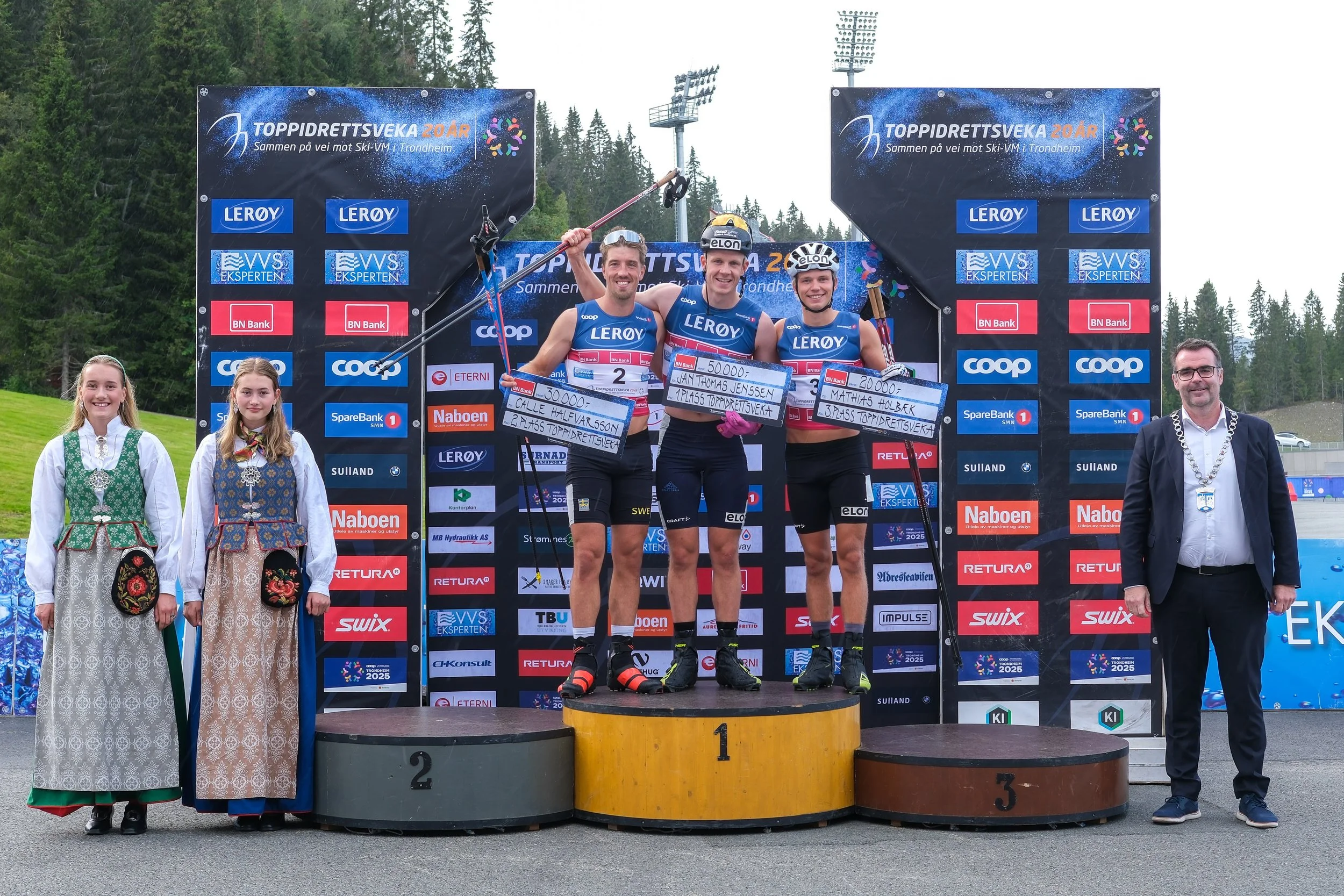 Premiepallen. Bakgrunnen viser et stort banner med informasjon om en skikonkurranse.