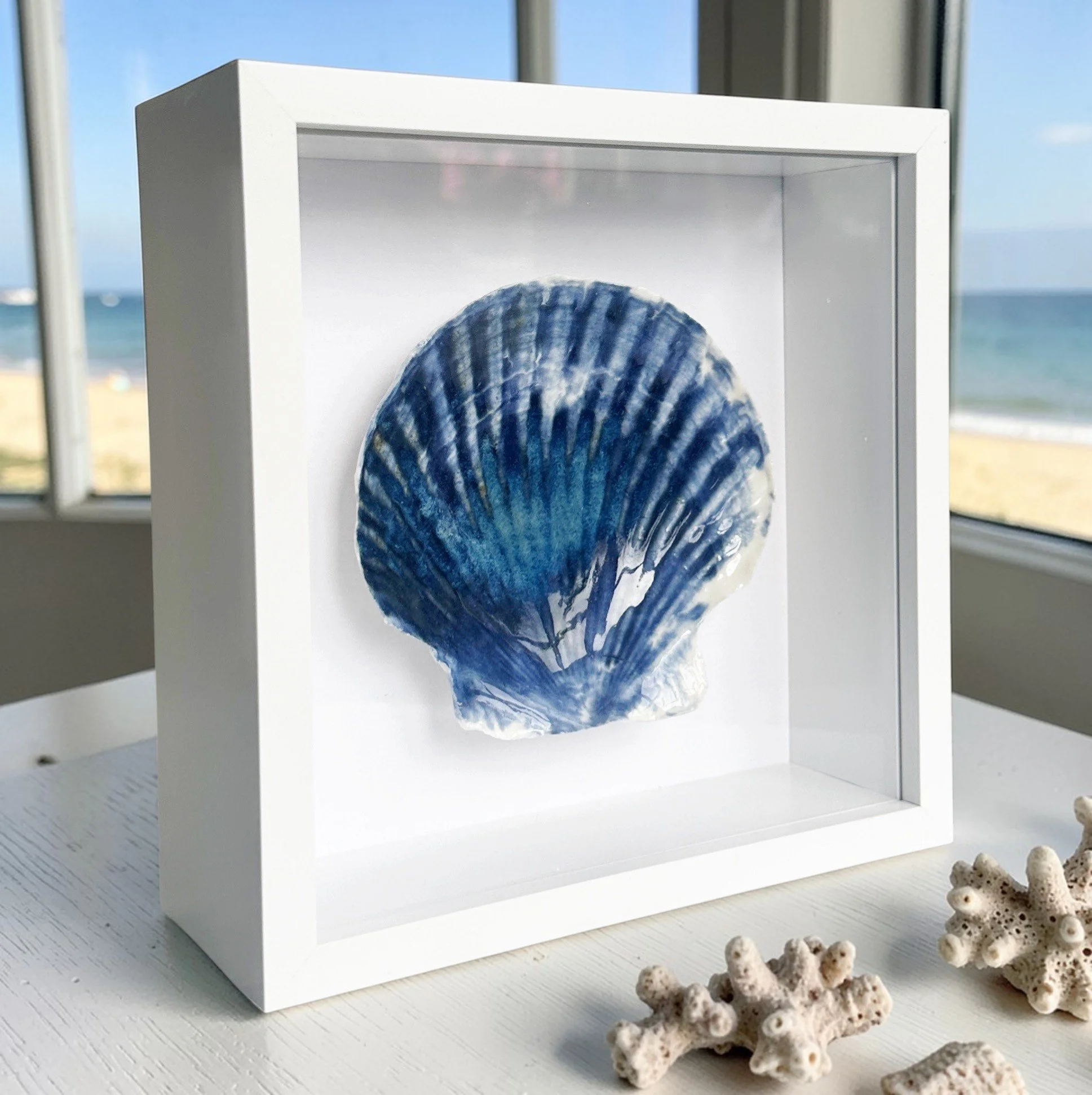 This textured coastal wall art features handcrafted porcelain shell art, creating a unique piece of beach art inspired by the Sussex coastline