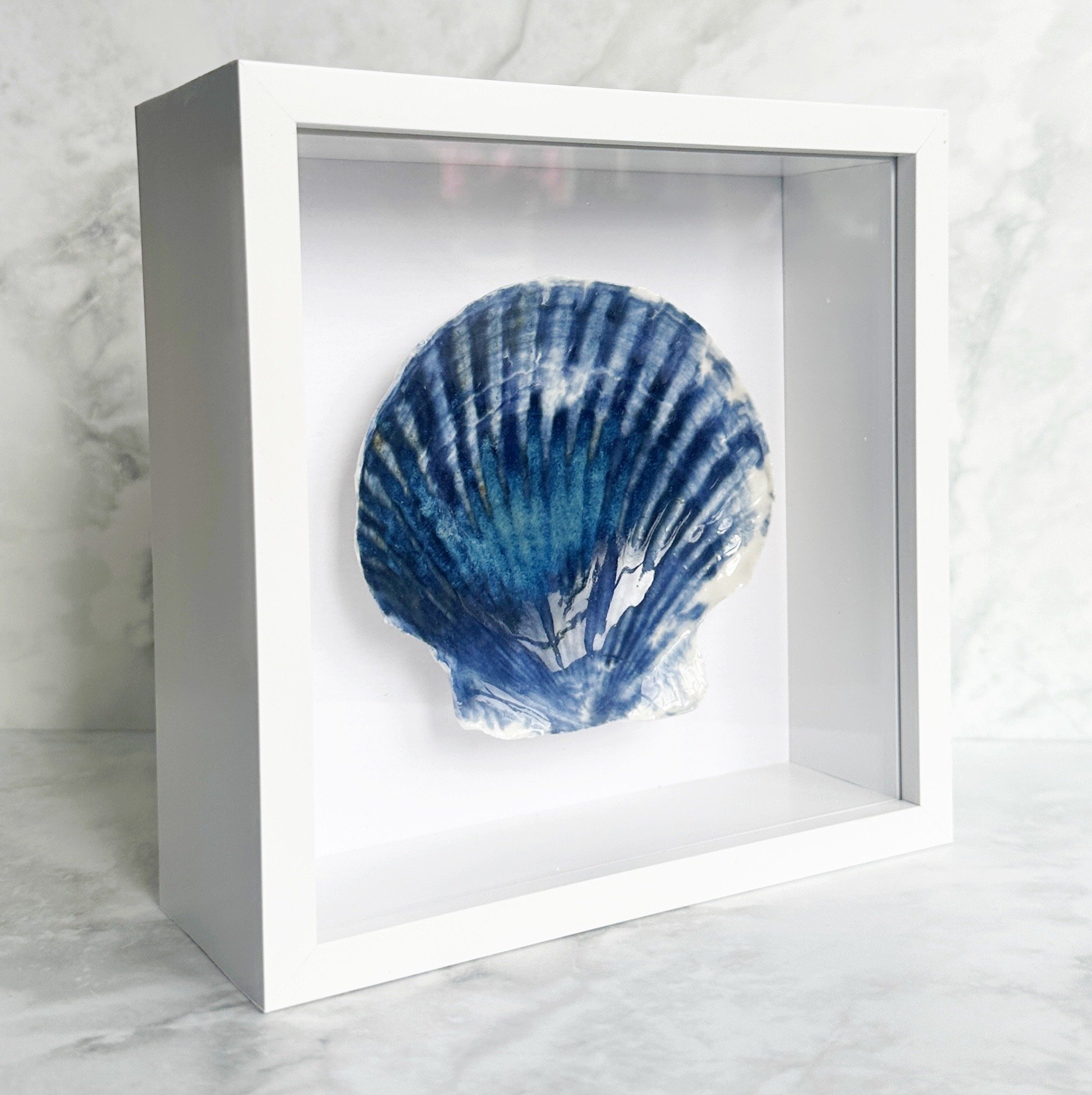 This textured coastal wall art features handcrafted porcelain shell art, creating a unique piece of beach art inspired by the Sussex coastline