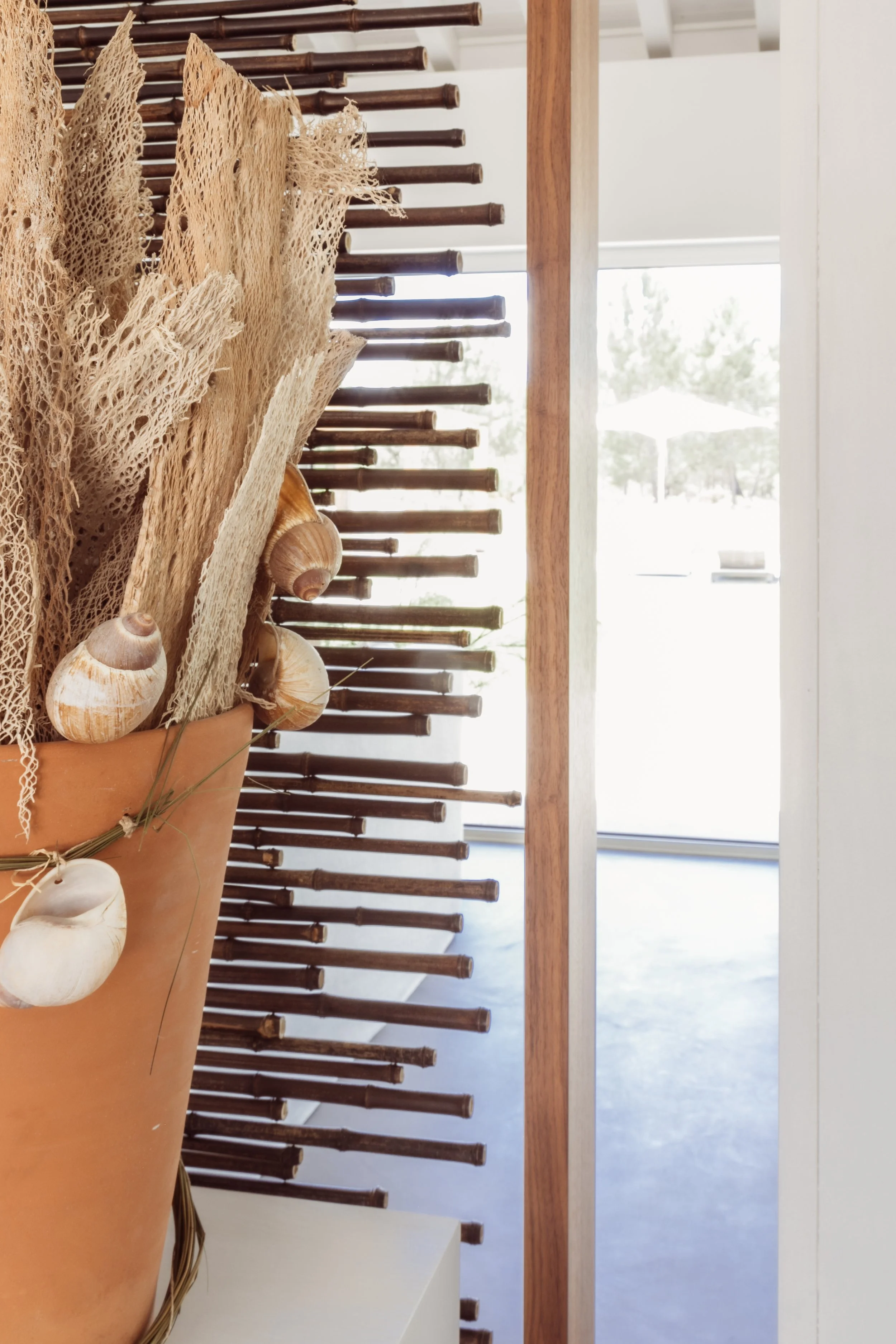 Decorative dried sea sponges, shells, and dried plant arrangement in a large terracotta vase.