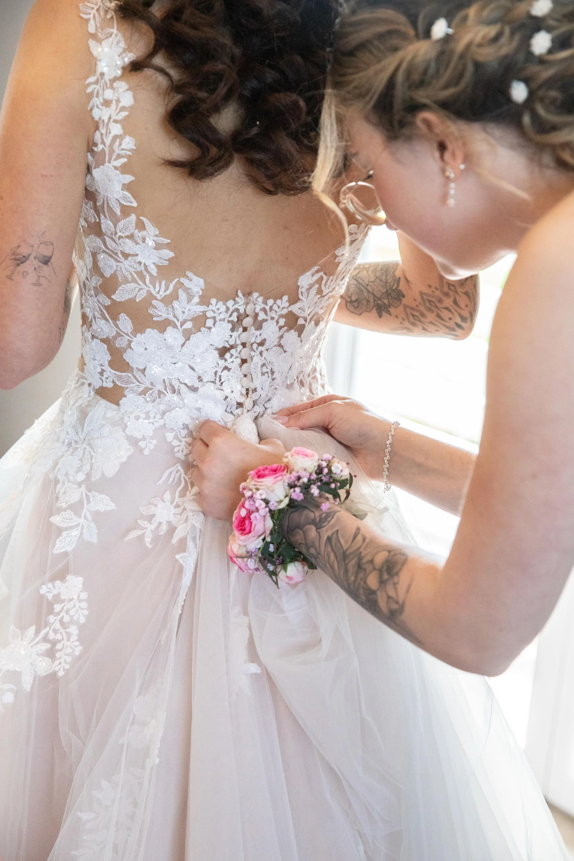 getting ready die Trauzeugin macht der Braut das Kleid zu