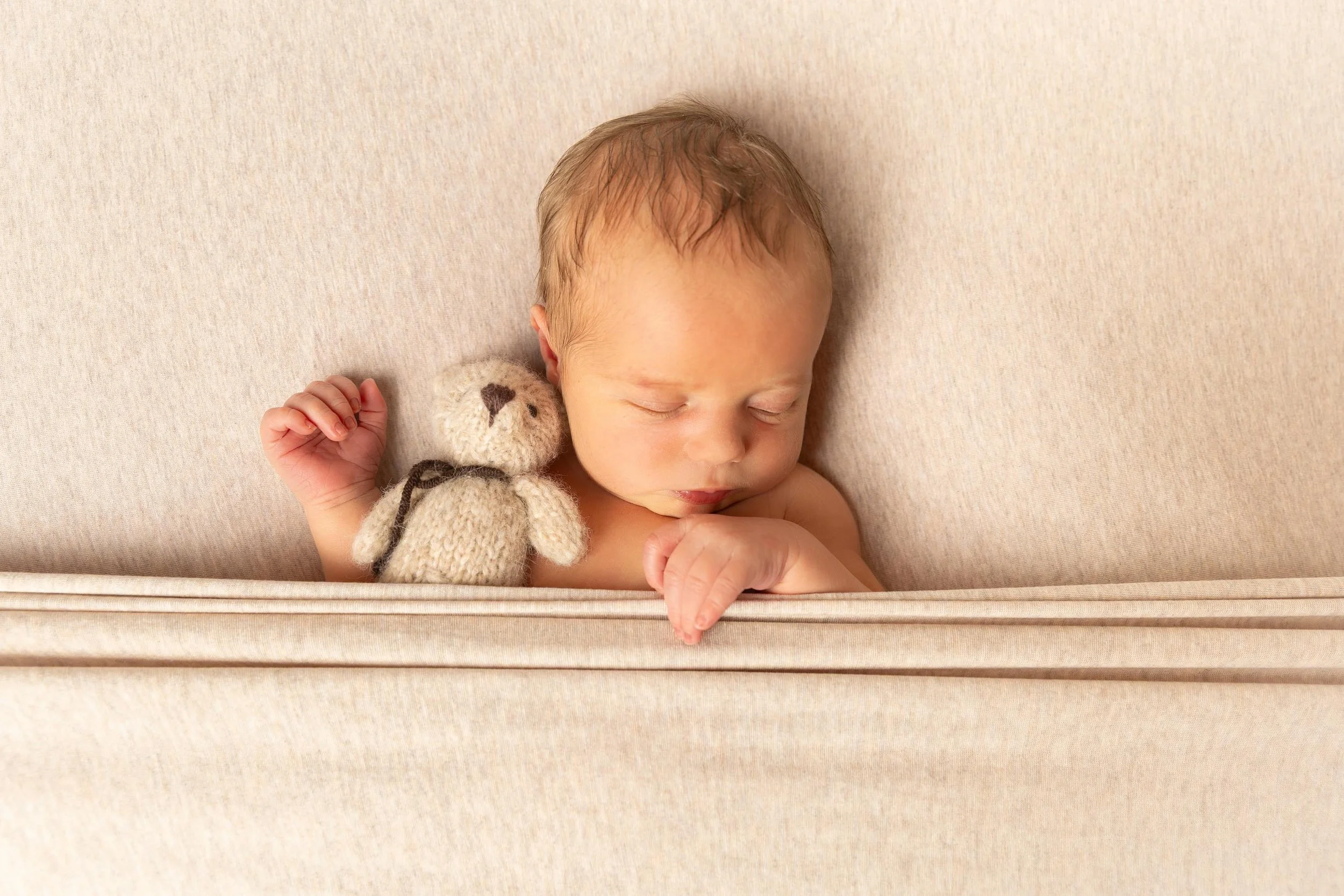 neugeborener Junge eingekuschelt mit Teddybär