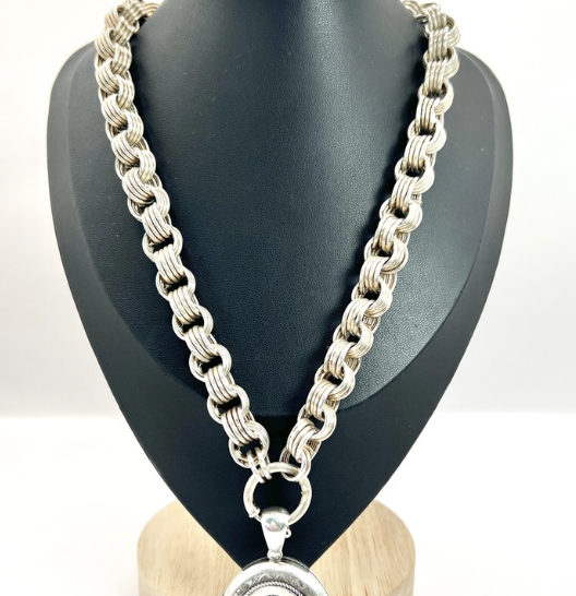 Silver book chain necklace with a large locket pendant on a black display bust.
