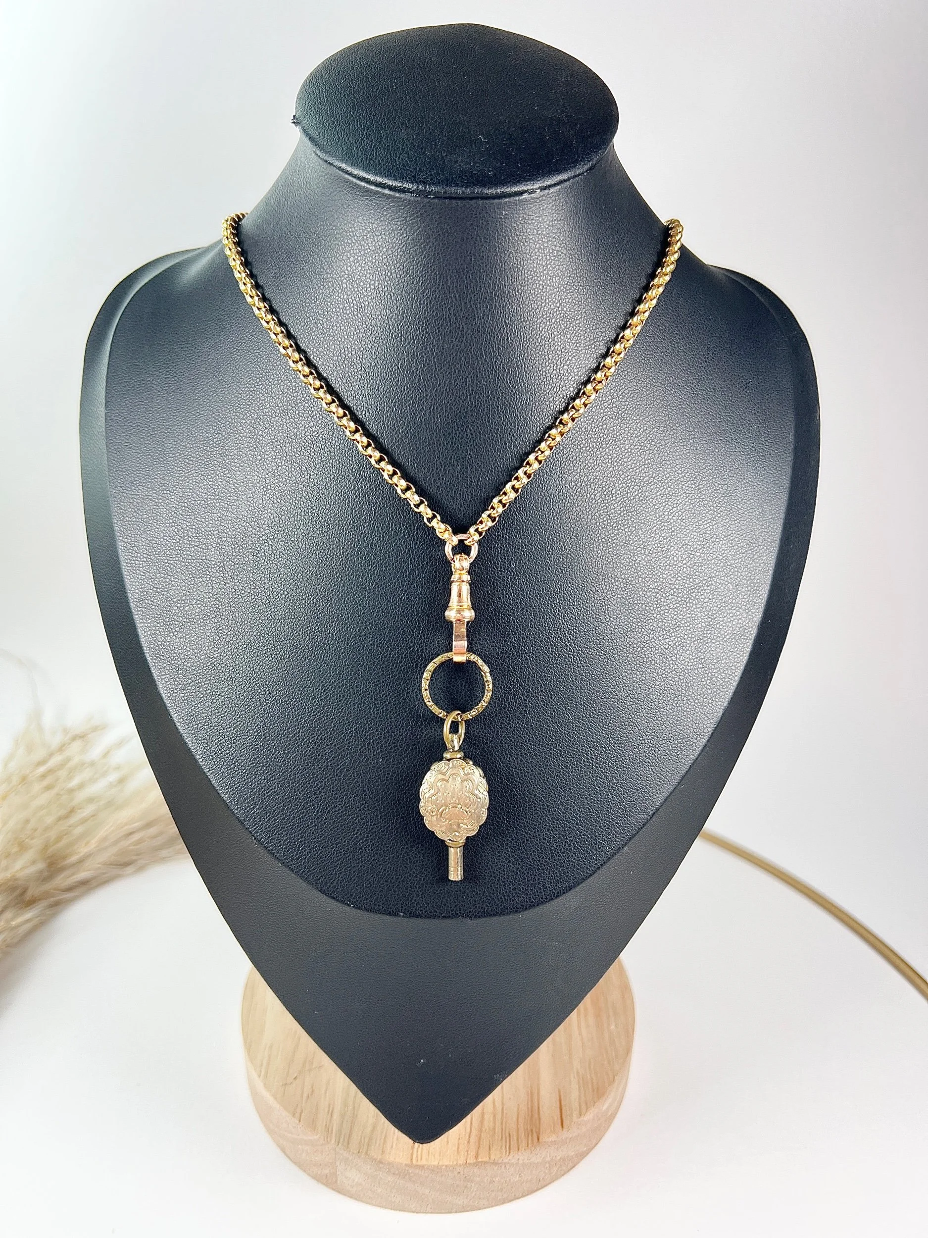 Gold chain necklace with an antique key pendant suspended from the bottom.