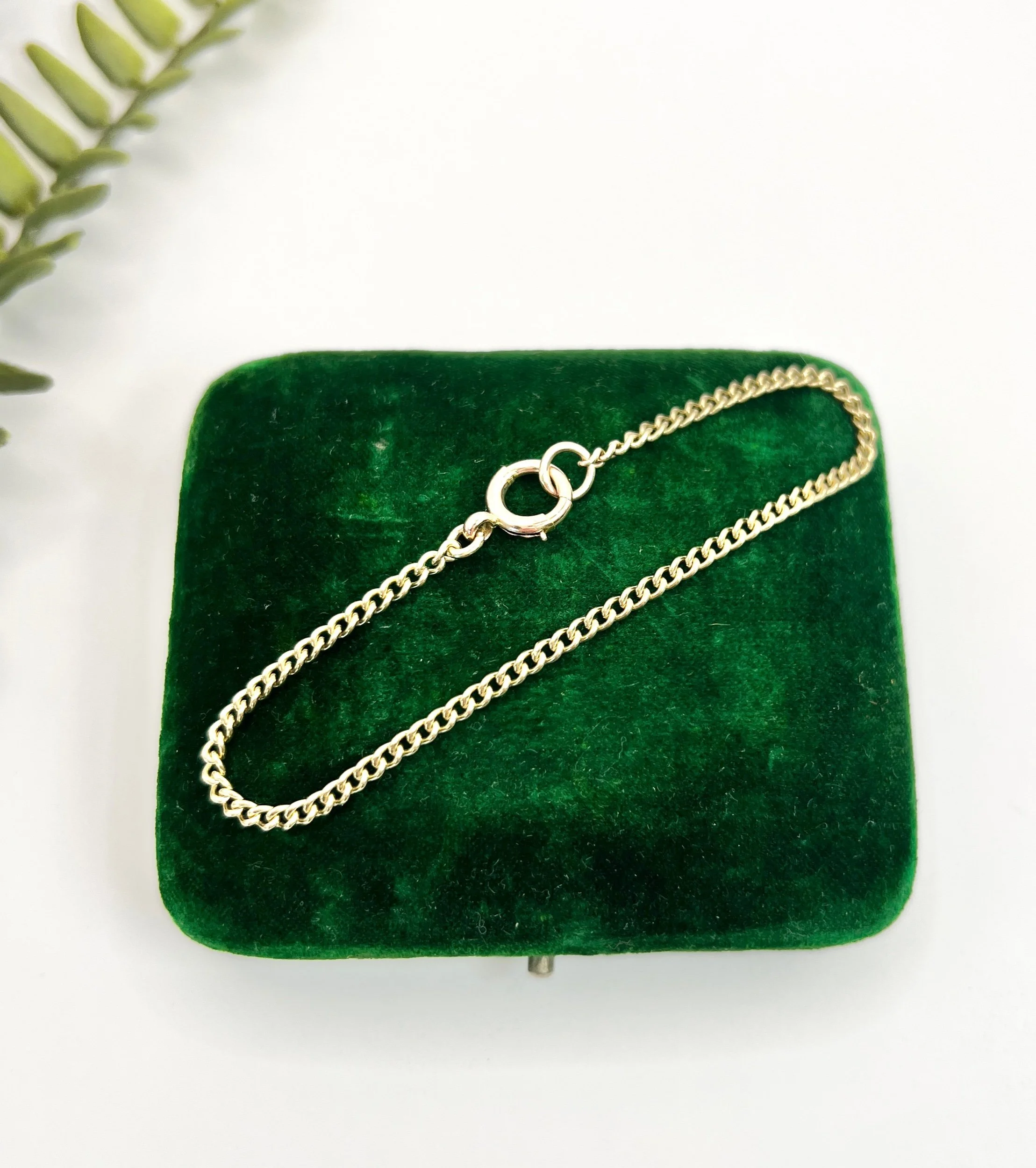 Gold chain bracelet on a green velvet jewellery box