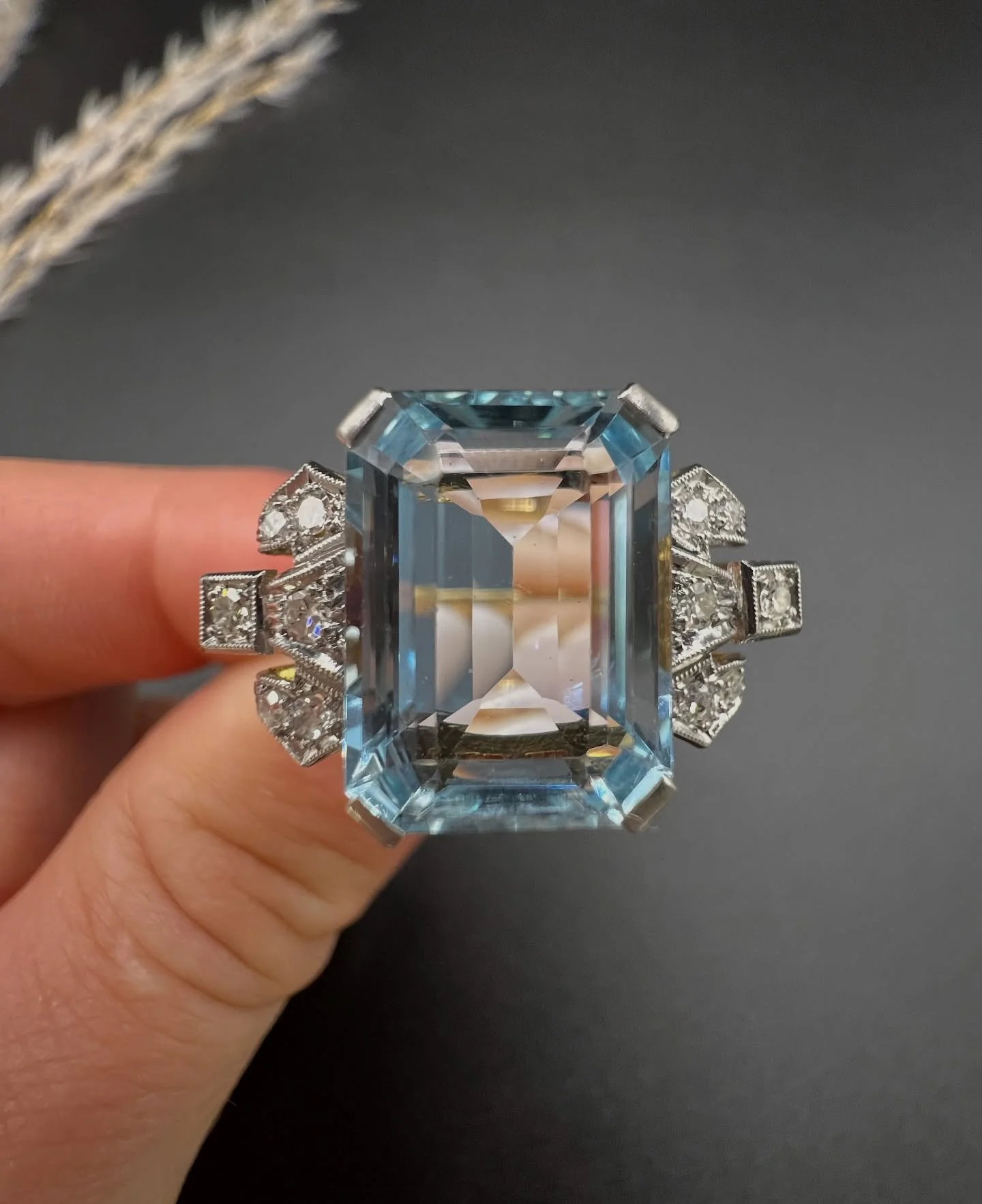 π πΈπ» Aquamarine Queen πΈπ»π 
This fabulous 1920s cocktail ring, is a true testament to the elegance of the era. At the heart of this exquisite piece lies a mesmerising emerald-cut natural aquamarine stone flanked by statement design milgrain-set d