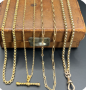 Various gold chains displayed on a wooden jewelry box.