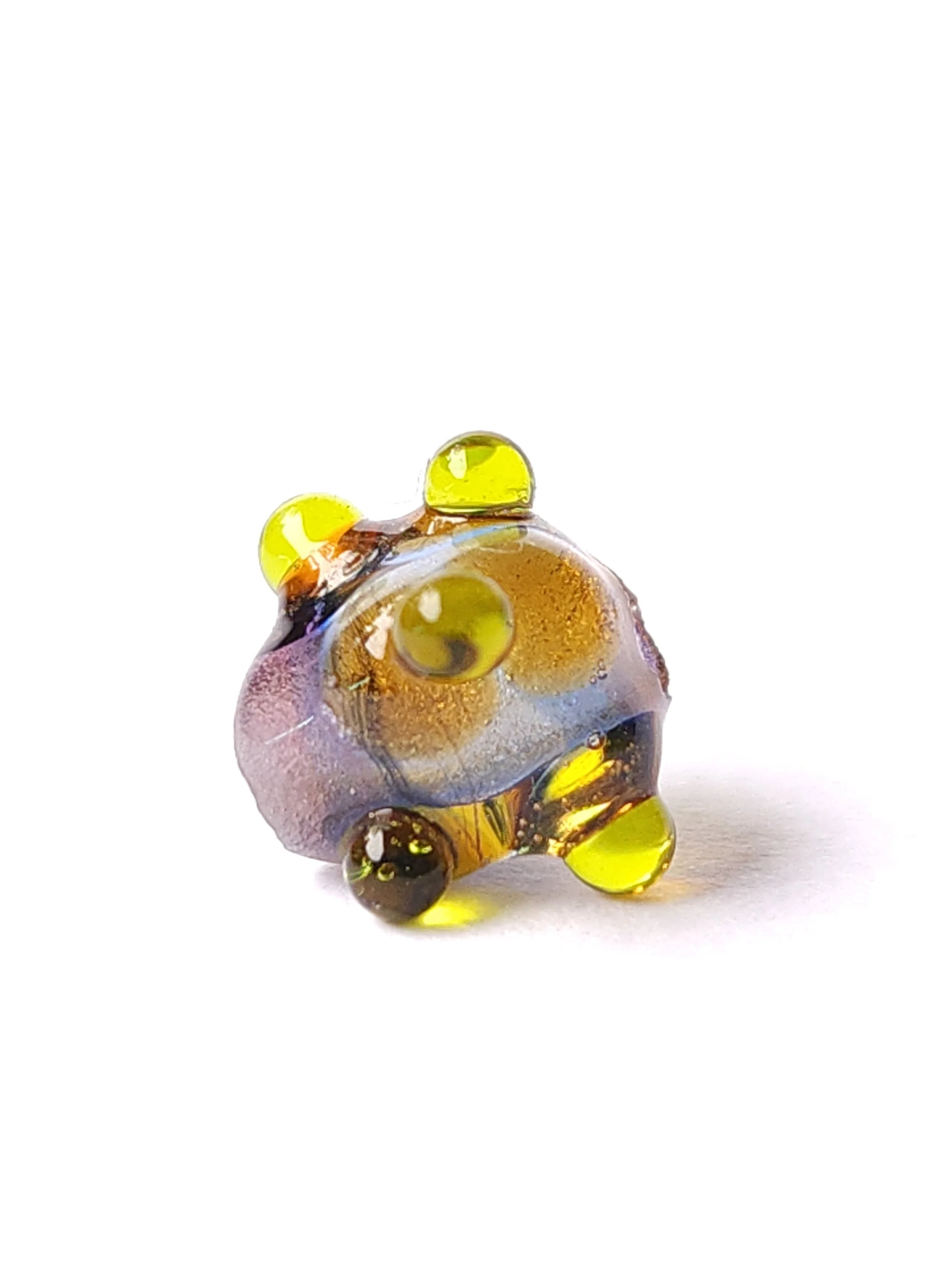 Transparent glass lampworked bead. Multicolor base with yellow dots. Close up image of glass bead. 