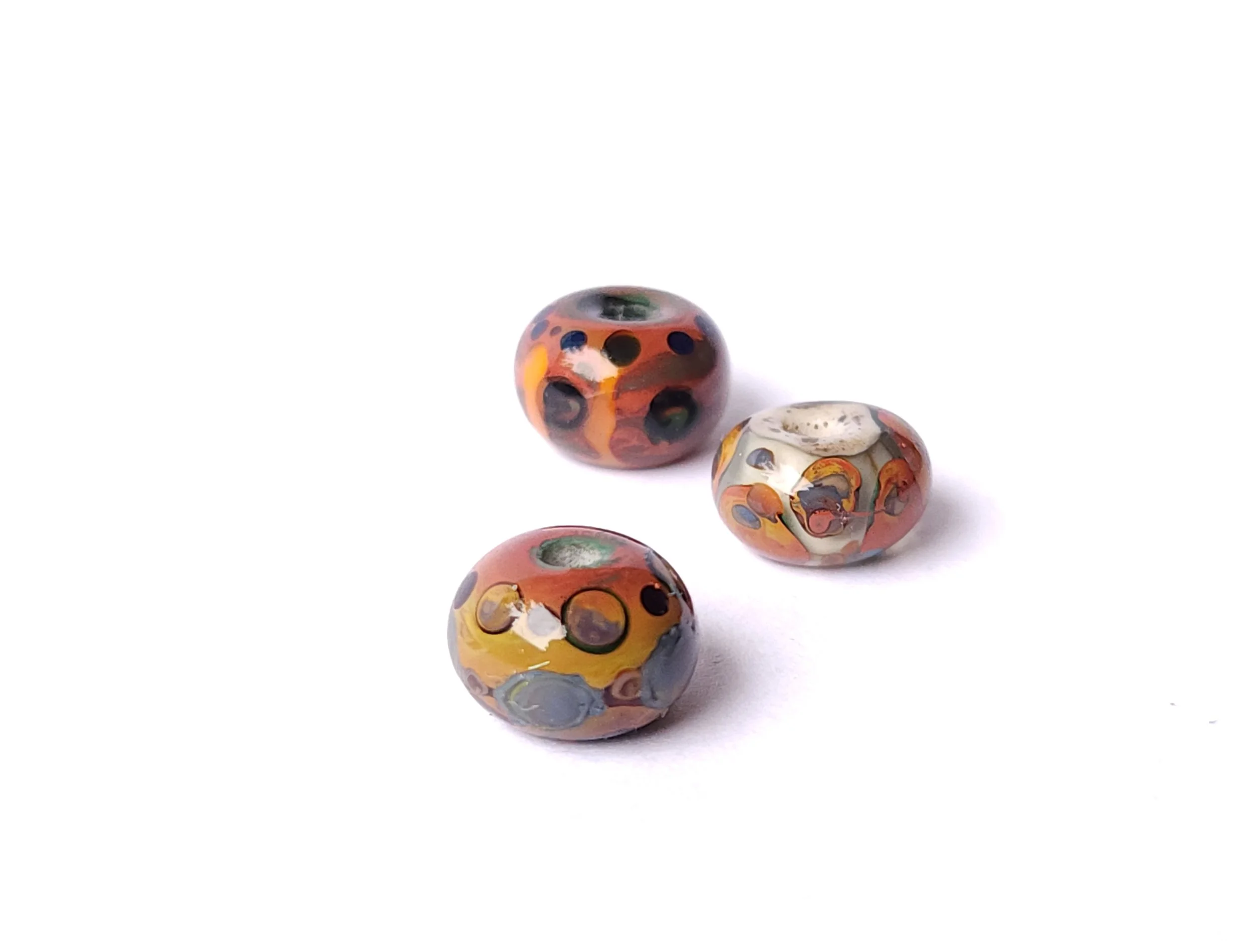 Selection of glass lampworked beads in natural earth tones. Dot designs.