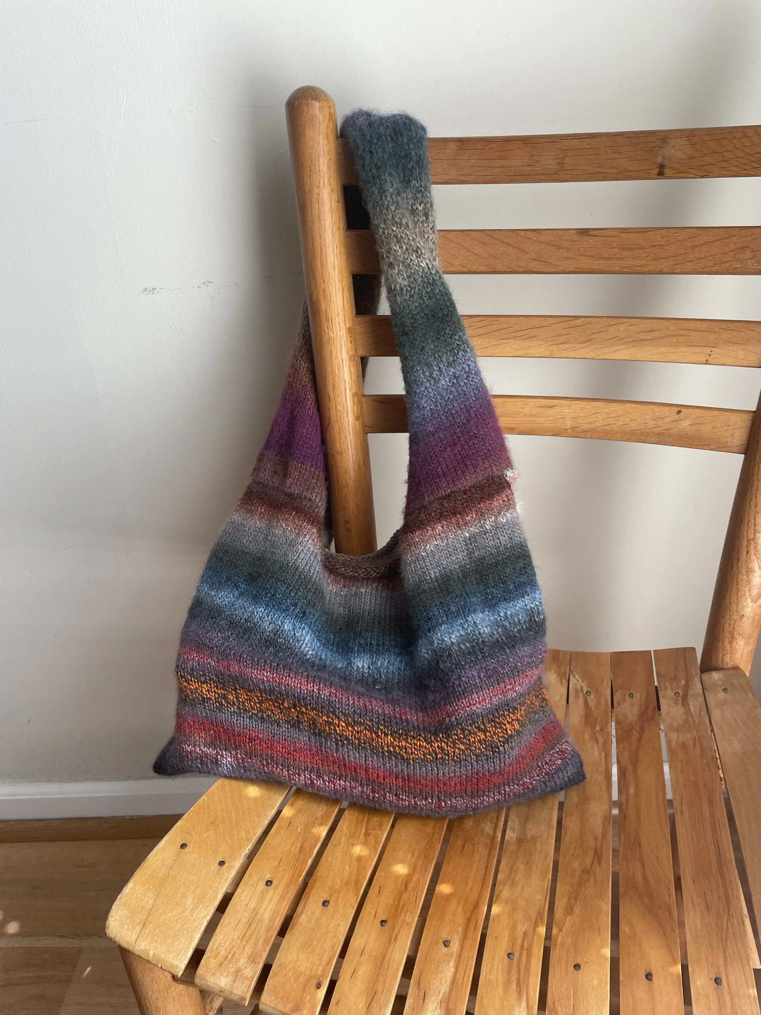 Multicolored knit bag draped over a wooden chair