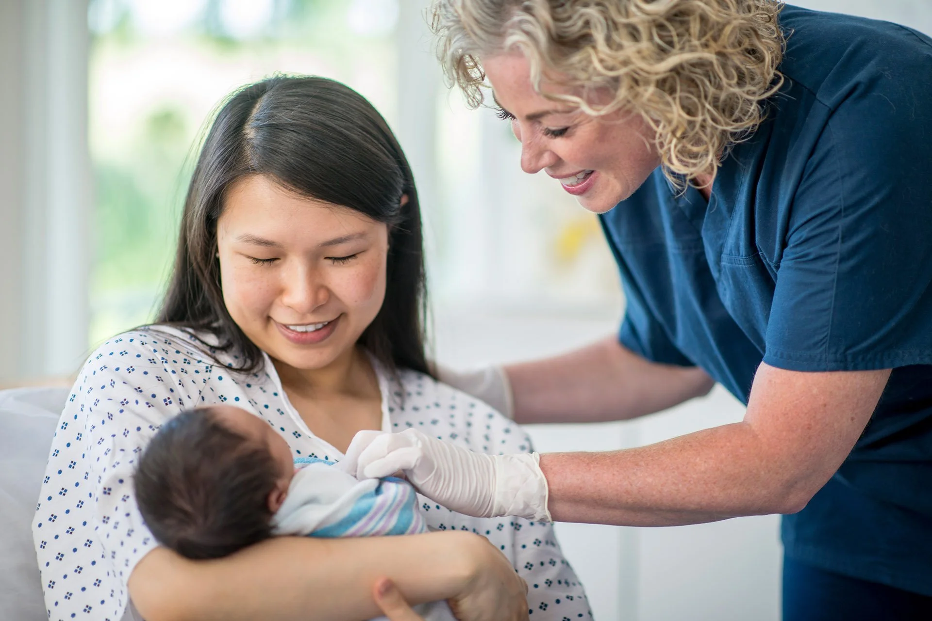 Nurse and new mother smiling at newborn baby.jpeg