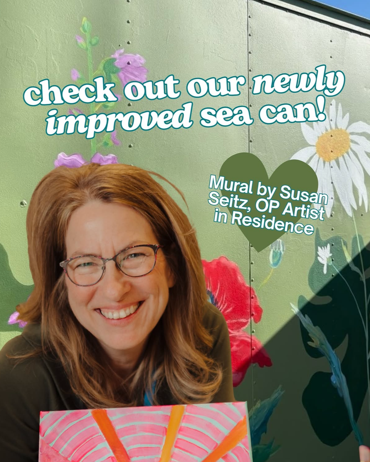 A woman with glasses smiling in front of a painted mural wall with flowers, holding a colorful small sea can, advertising a new sea can with text about the mural by Susan Seitz, OP Artist in Residence.