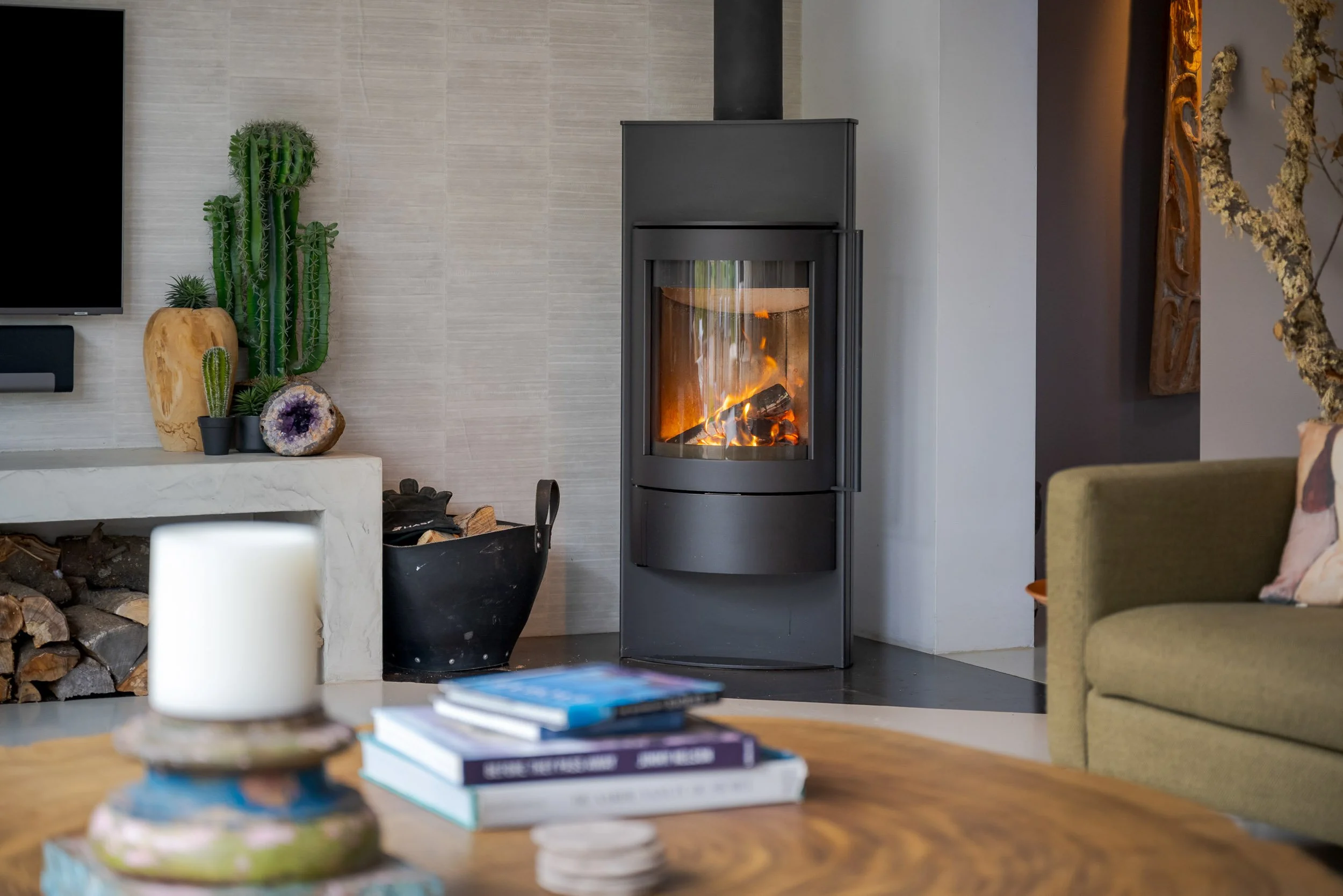 Moderne woonkamer met een houtkachel, planten en boeken op een tafel.
