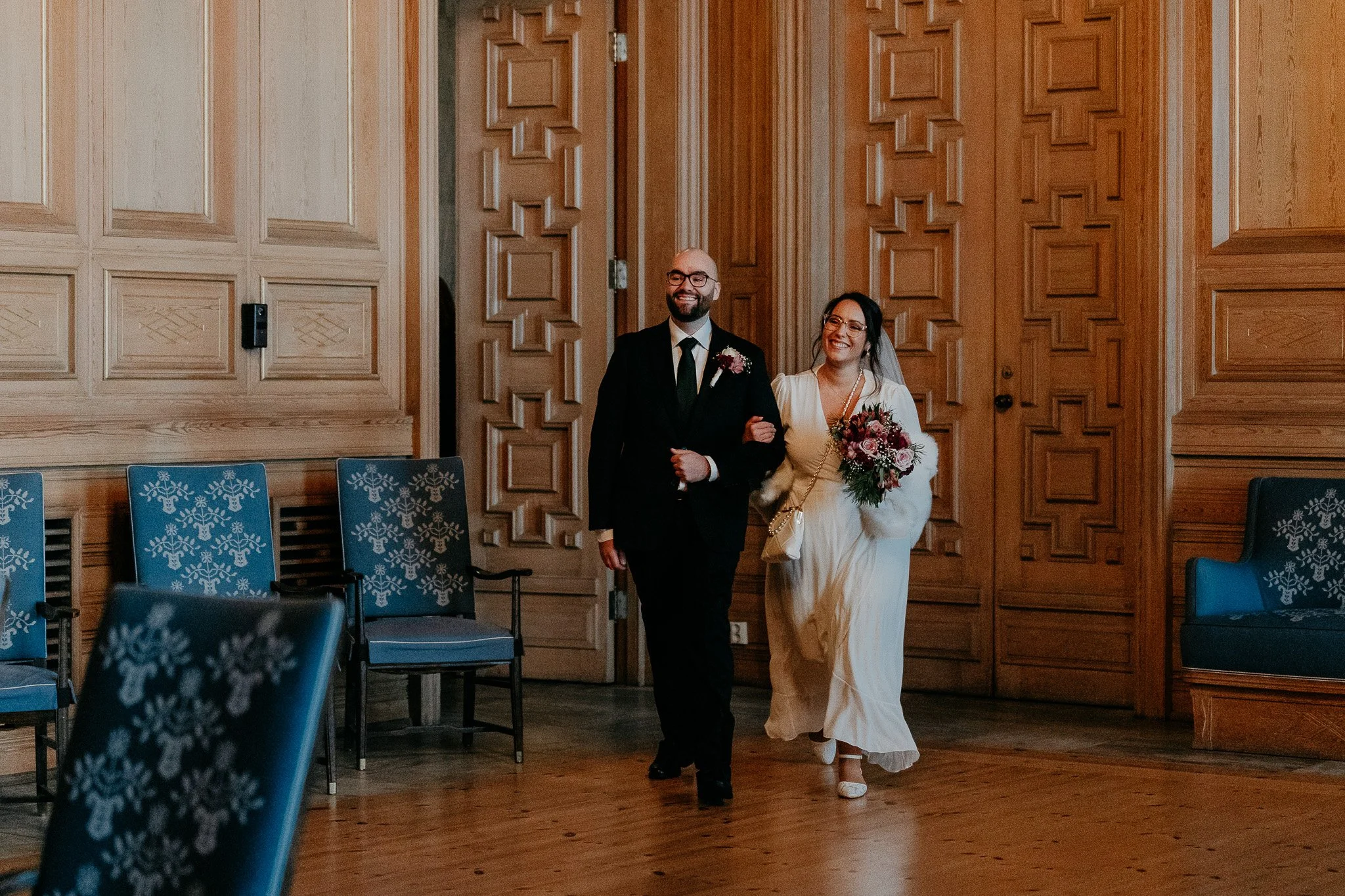 Et brudepar går arm i arm inn dørene til vigselssalen på Oslo rådhus.