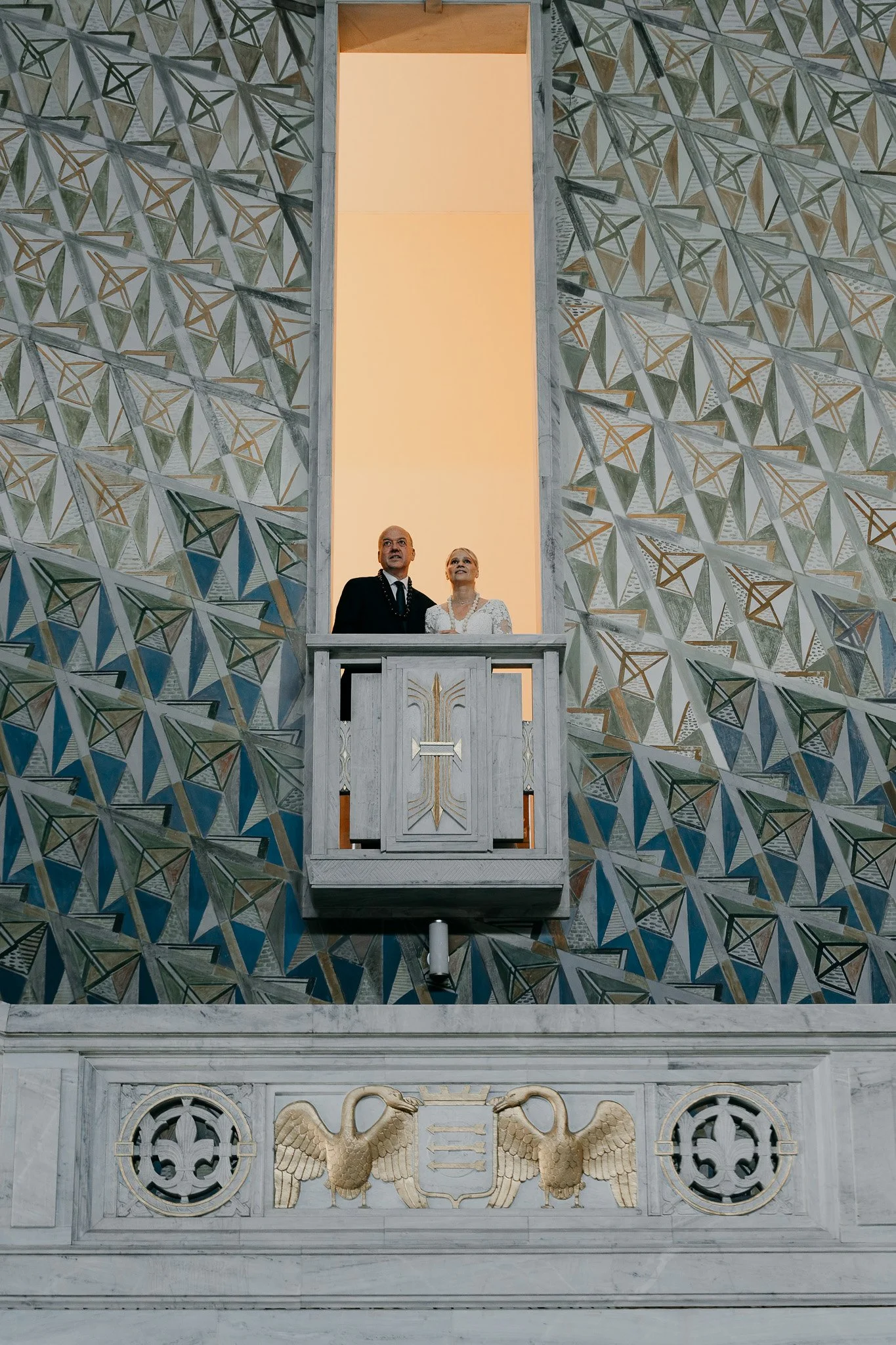 Et brudepar står i en åpning i veggen på Oslo rådhus.