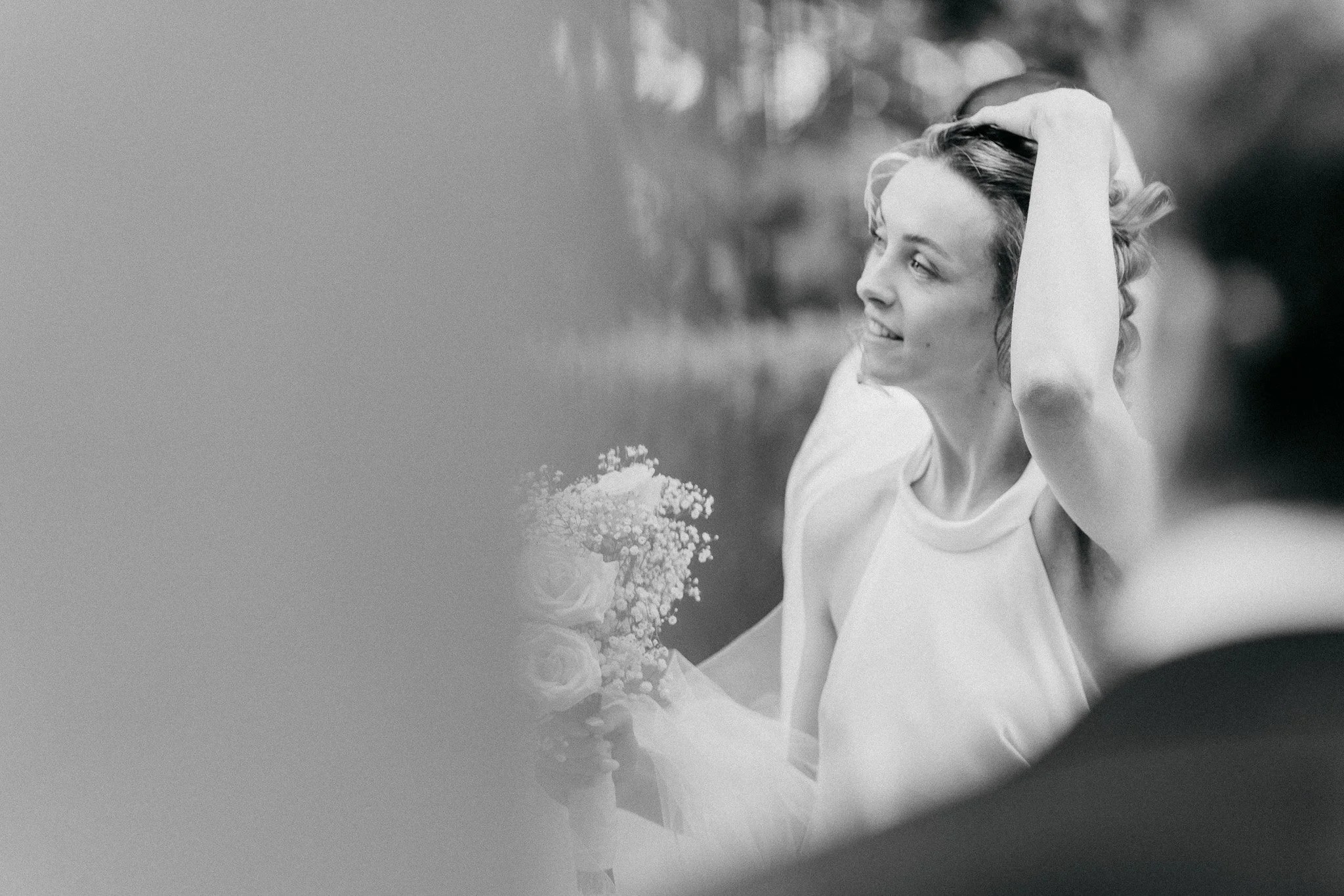 Sort-hvitt bilde av brud som holder en bukett og tar seg i håret.