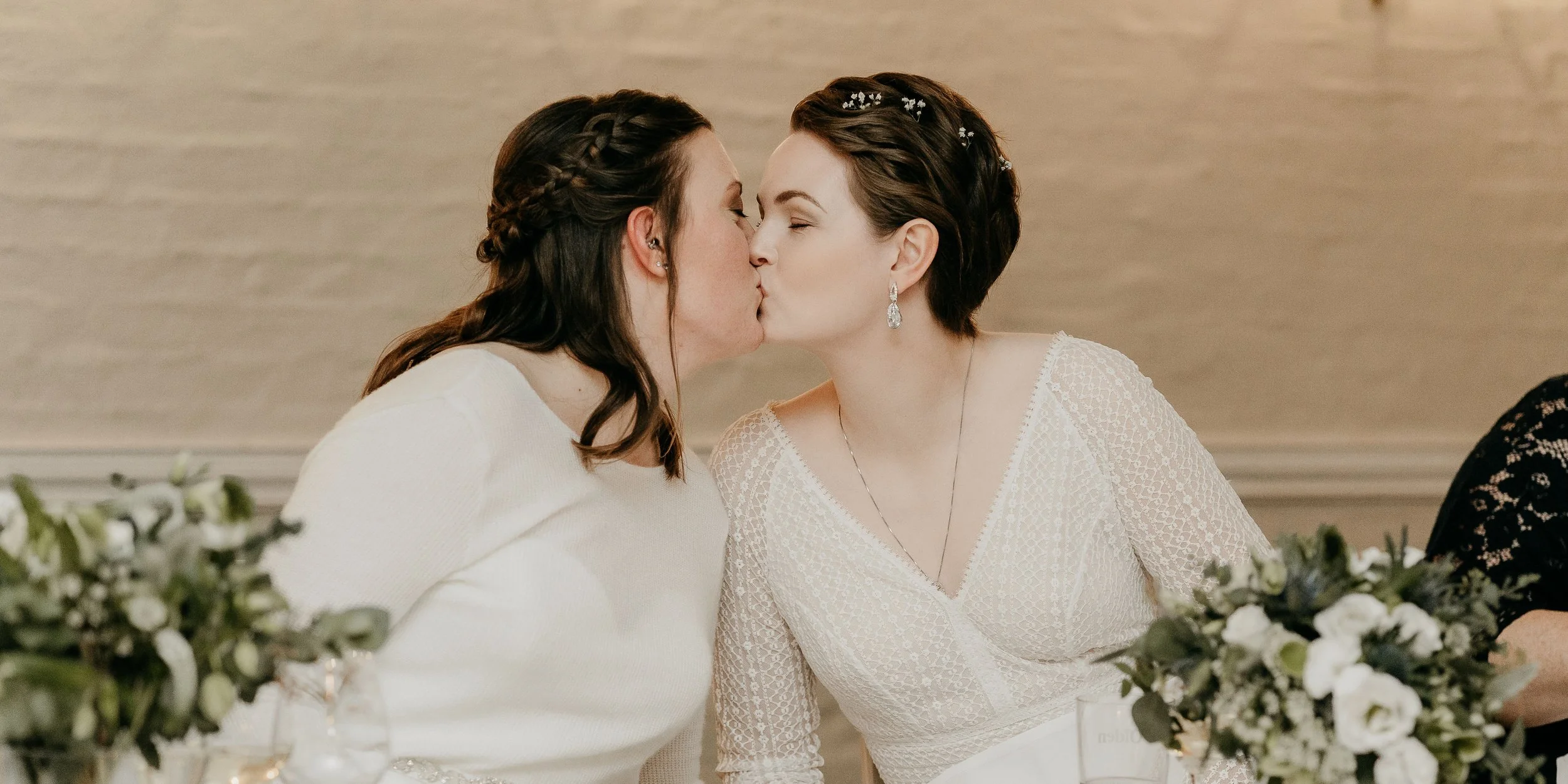 Two brides kissing on their wedding day.