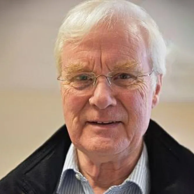 Close-up of an older man with glasses and gray hair in black and white.