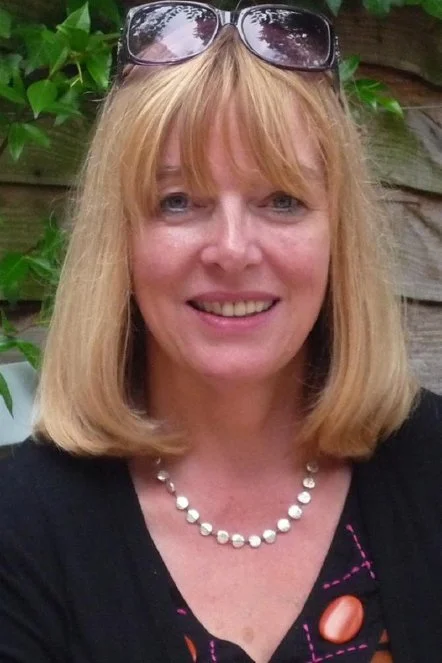 Black and white photo of a woman with straight blonde hair and bangs, smiling slightly.