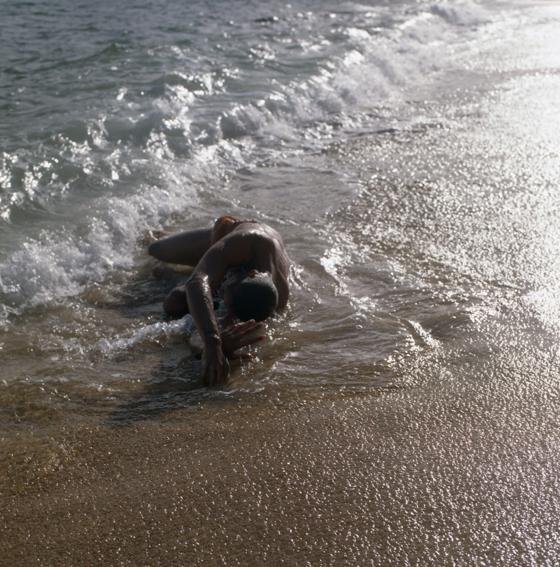 sukhpreet's photography of a melanated person laying in the ocean waves
