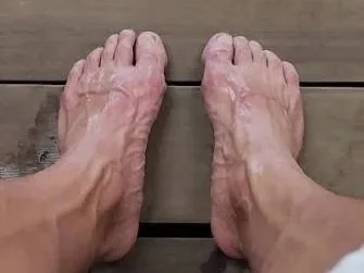 Close-up of a person's bare feet on a wooden floor.