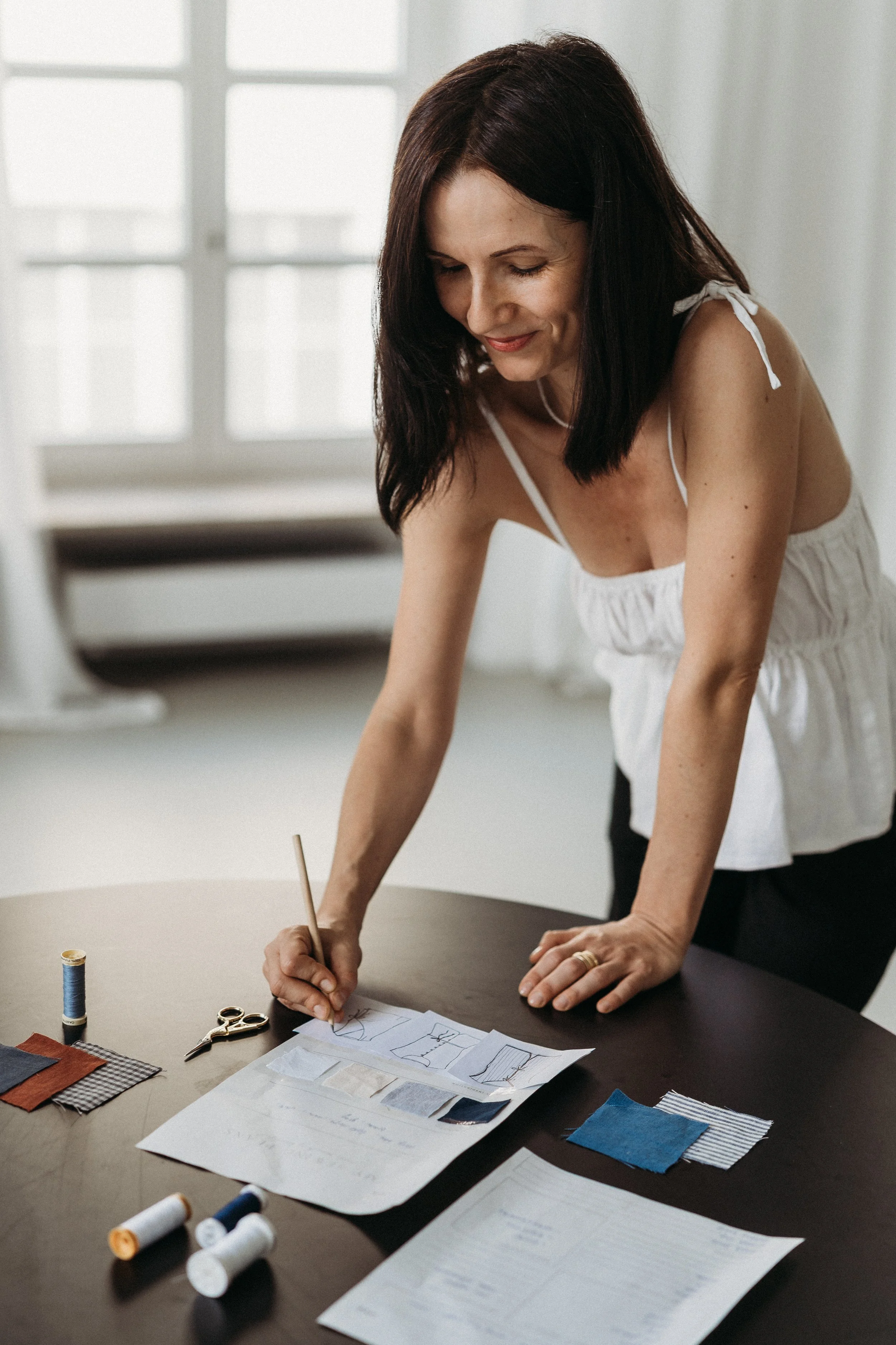 Frau gestaltet Schnittmuster und Stoffproben an einem Tisch.