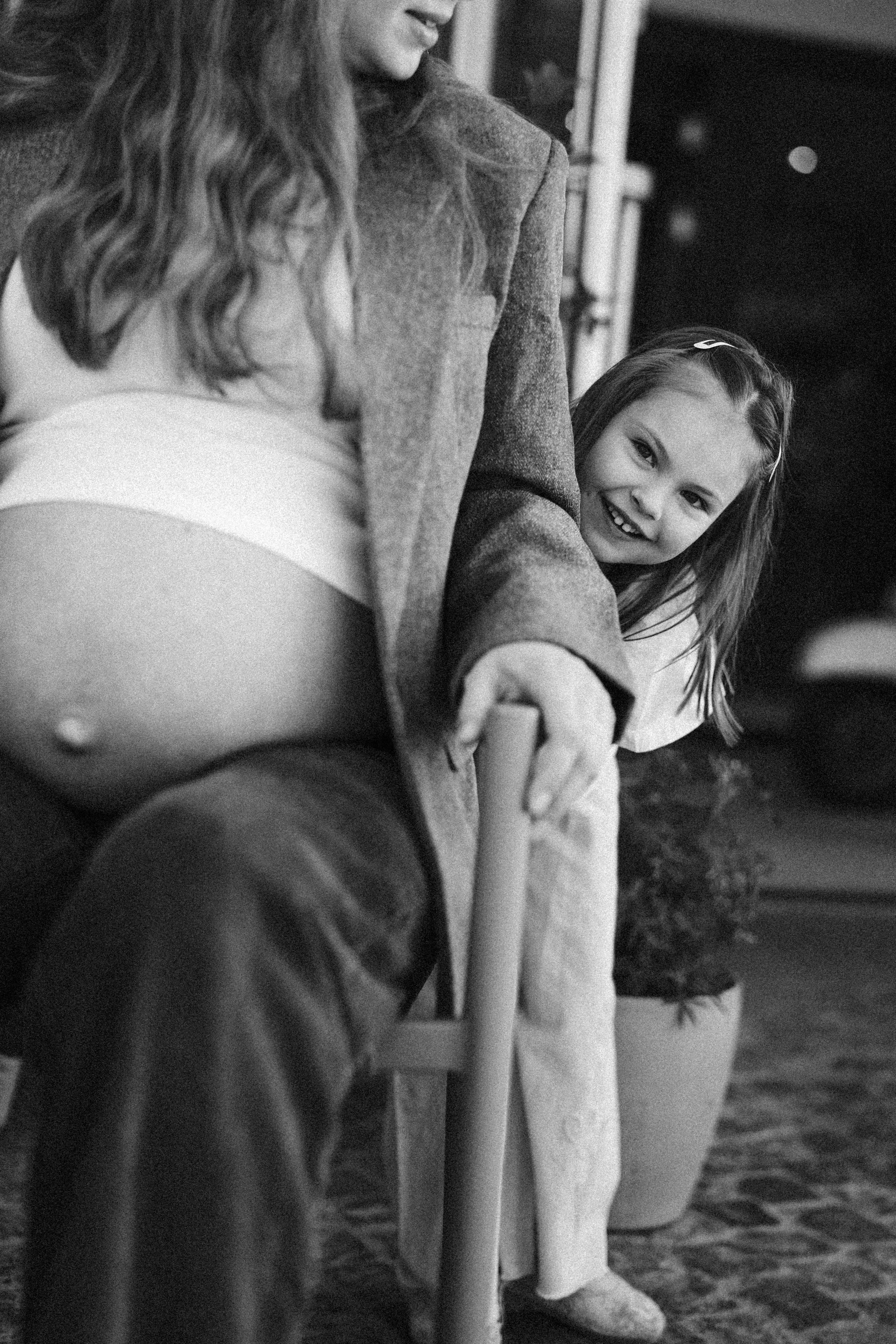 Zwei Mädchen sitzen an einem runden Tisch, eines lächelt in die Kamera, das andere betrachtet etwas außerhalb des Bildes. Es ist ein Schwarz-Weiß-Foto.