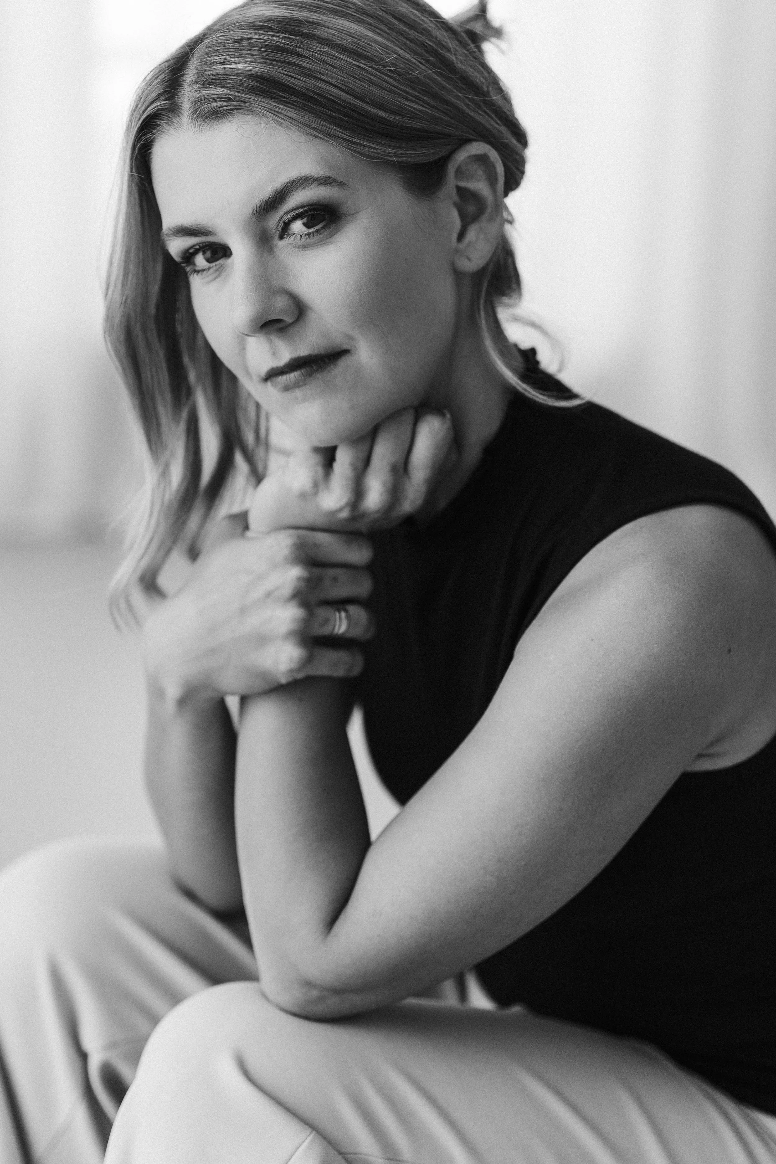 Schwarz-Weiß-Fotografie einer Frau, die mit der Hand ihr Kinn stützt, sommerlicher Look, kurzhaariges Haar, entspannte Pose