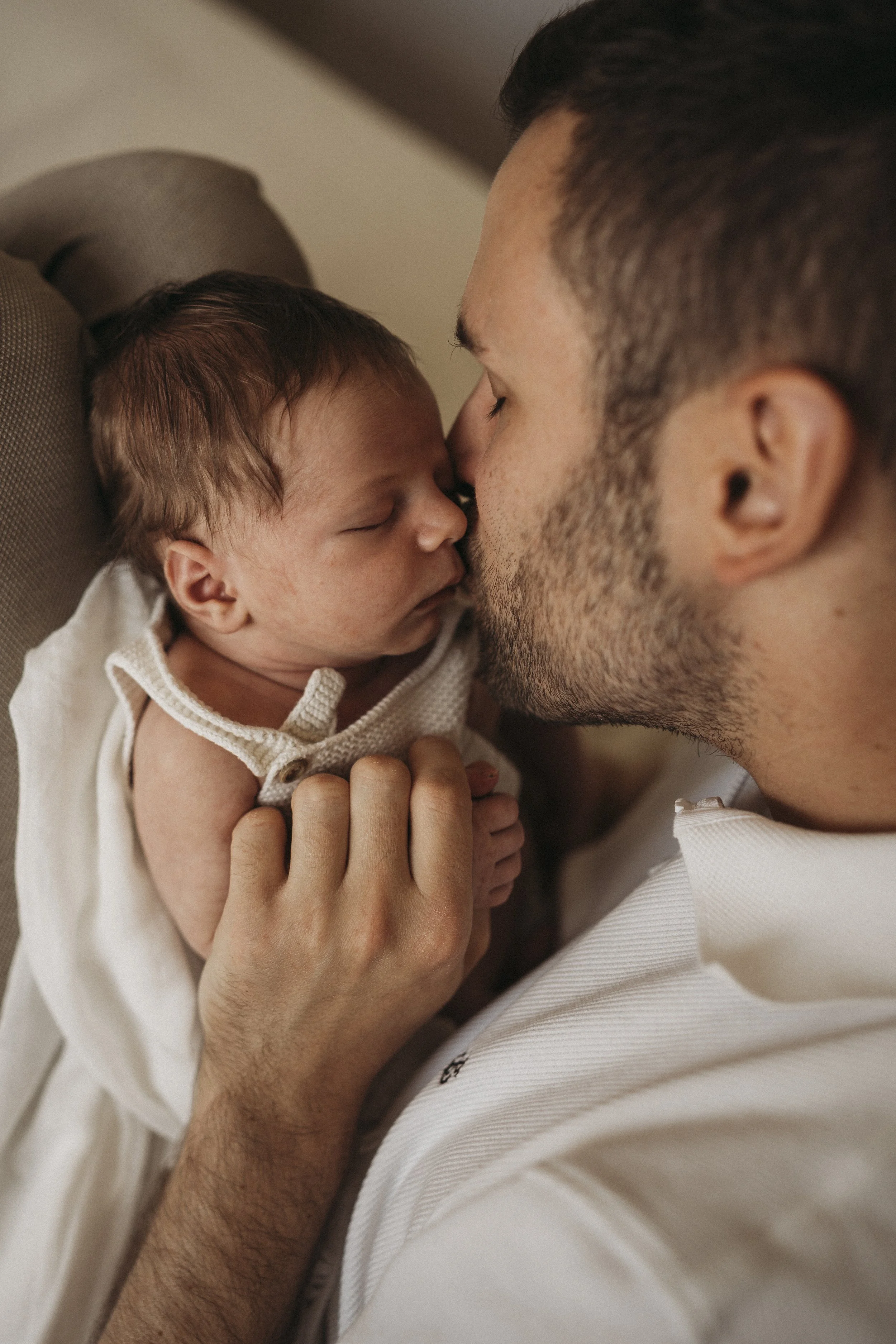 Ein Mann hält ein schlafendes Baby in den Armen, ihre Stirn berühren sich liebevoll.