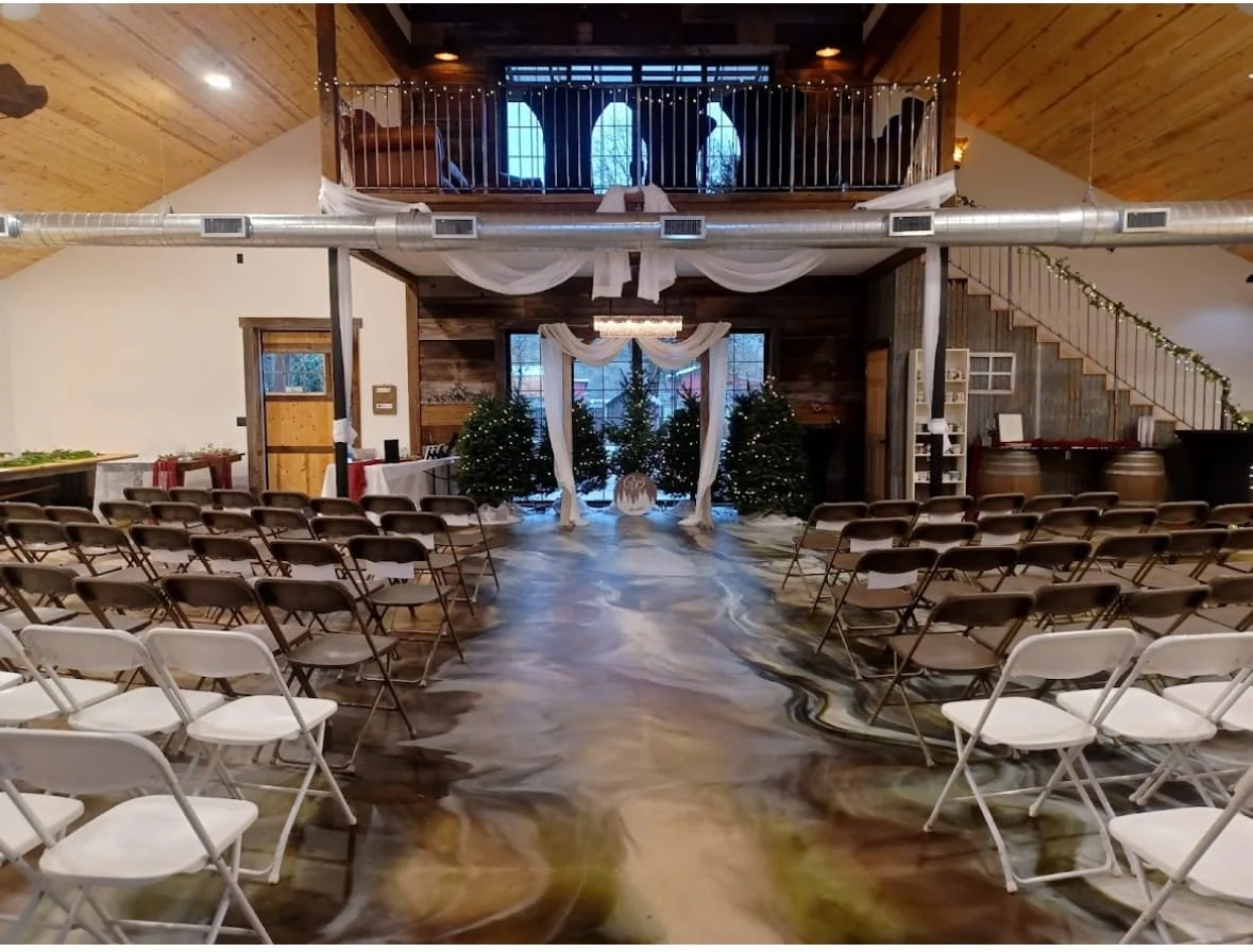 A couple in wedding attire standing on a second-story balcony of a wooden house with a red roof and black railings.